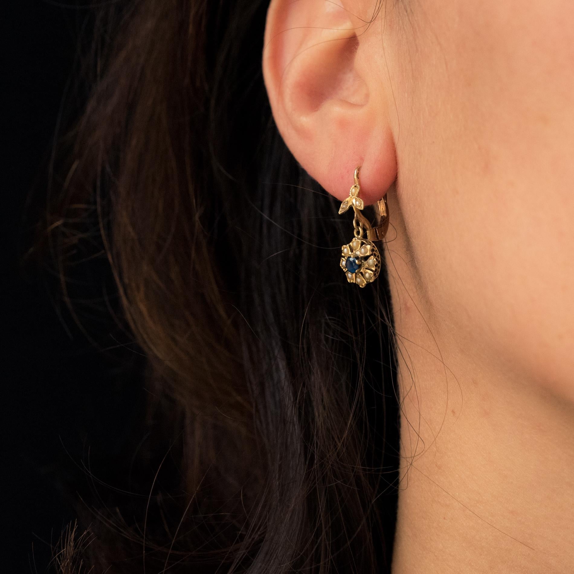 For pierced ears.
Earrings in 18 karat yellow gold, eagle's head hallmark.
Lovely antique ear pendants, they consist of a leaf motif each set with 3 natural half-pearls. It retains a floral motif set in the center and with claws of a sapphire