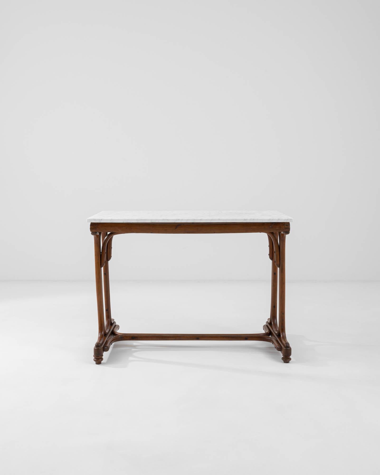 A wooden side table with a marble top created in 1900s France. Charmingly rustic, yet with a surprisingly modern flair, this charming bistro table blends aesthetics to an eye-pleasing effect. Carefully steam-bent wood harkens to the ‘Thonet’ style,