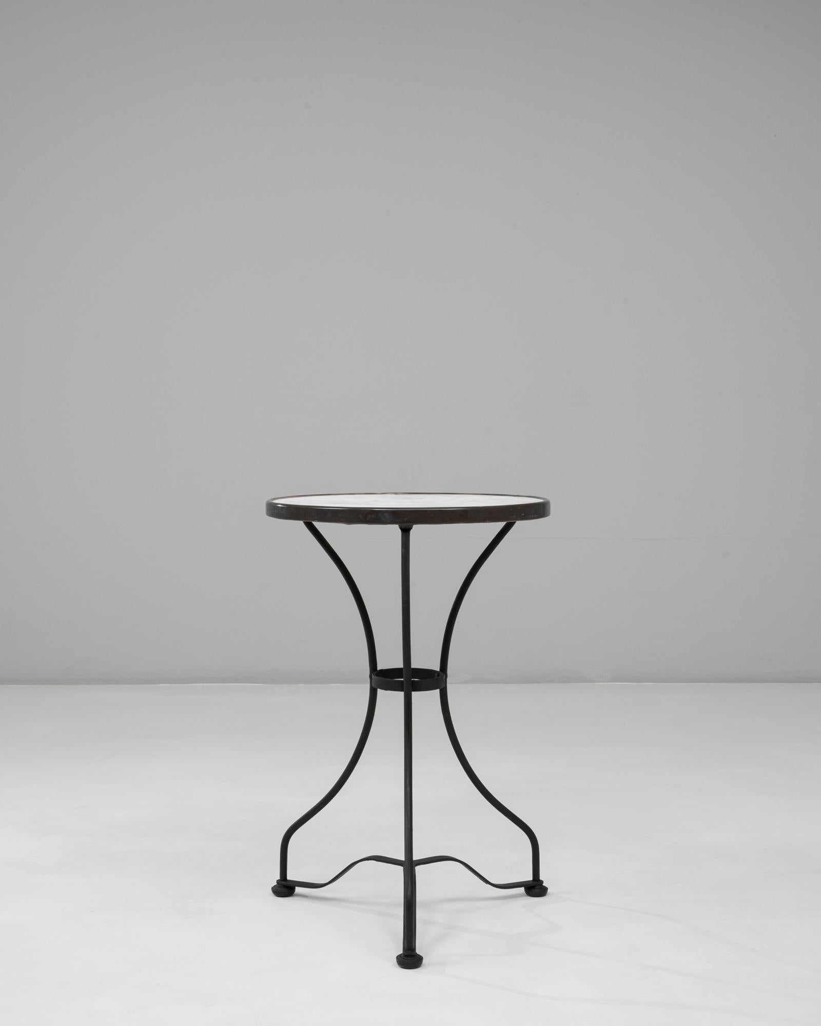 Cette table en fer de style bistro français des années 1900 avec plateau en marbre capture le charme et la fonctionnalité des premiers meubles de café. La surface ronde en marbre, légèrement usée avec des veines subtiles, apporte un contraste