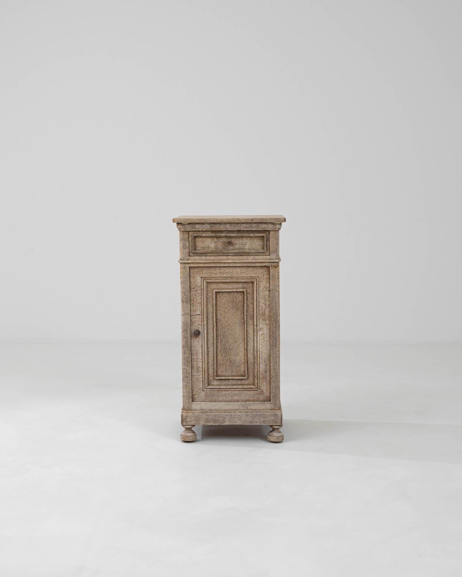 Presenting a charming slice of history with our 1900s French Bleached Oak Bedside Table. This exquisite piece carries the whispers of the past into the present with its beautifully weathered wood and graceful aging. Crafted during a time when