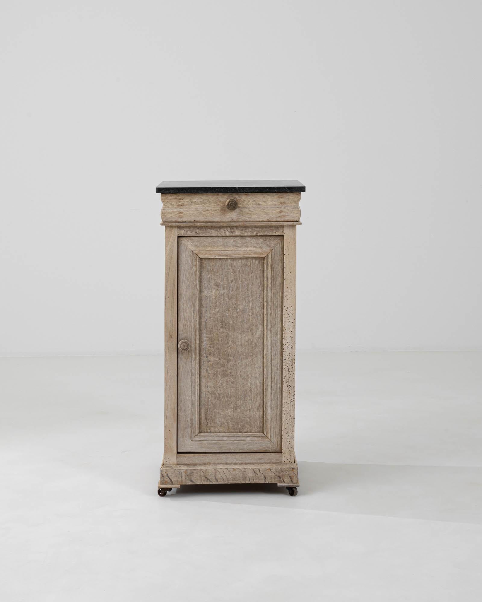 Introducing a piece of timeless elegance: our 1900s French Bleached Oak Bedside Table. Crafted with meticulous attention to detail, this elongated bedside table exudes understated sophistication. Fashioned from light oak, its light finish adds a