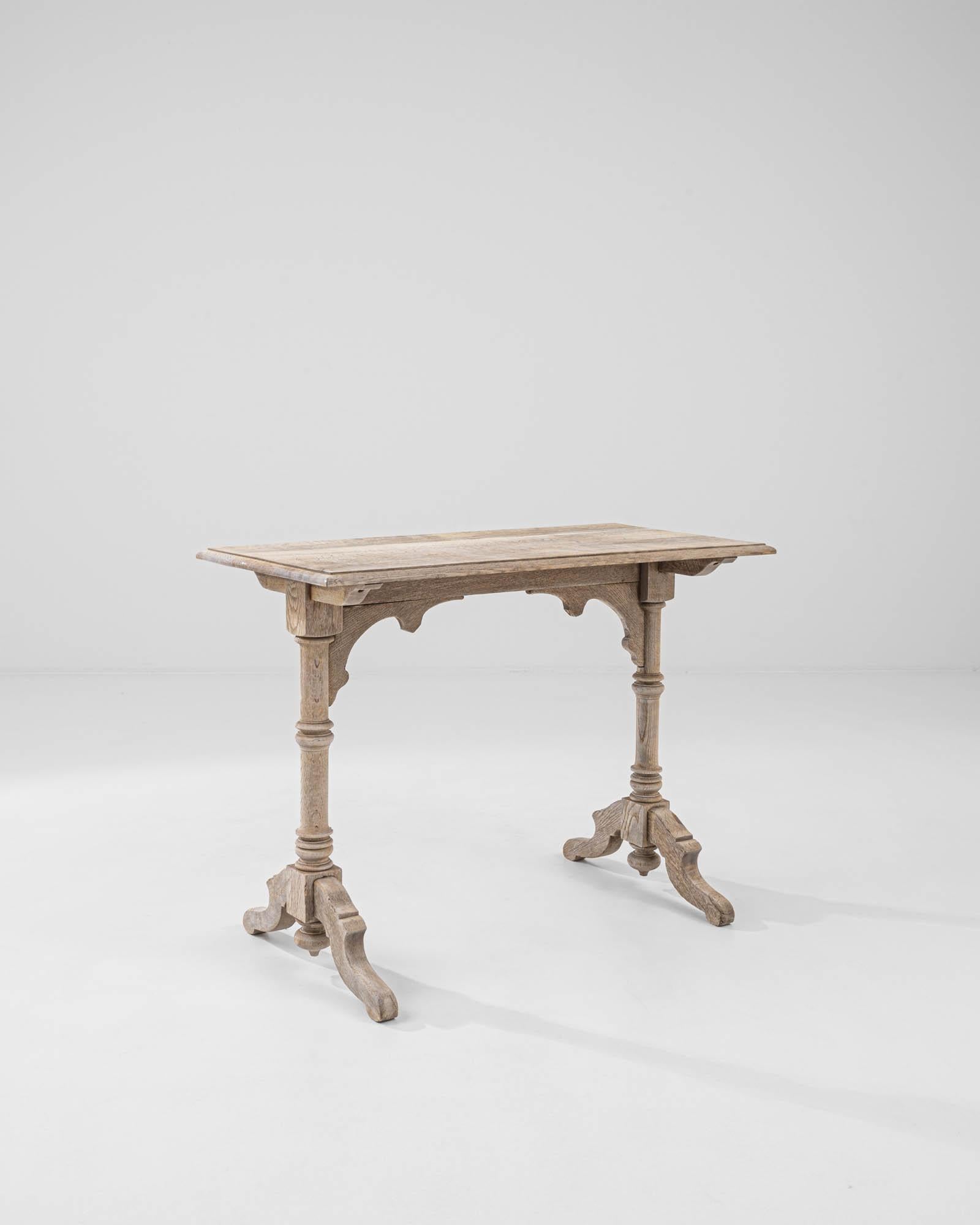 A wooden table from 1900s France. This small trestle table is composed of two legs with arching diagonal feet, carved with a rich attention to detail. The compact form is adapted to the necessities of bustling cafés and brasseries. The brightness of
