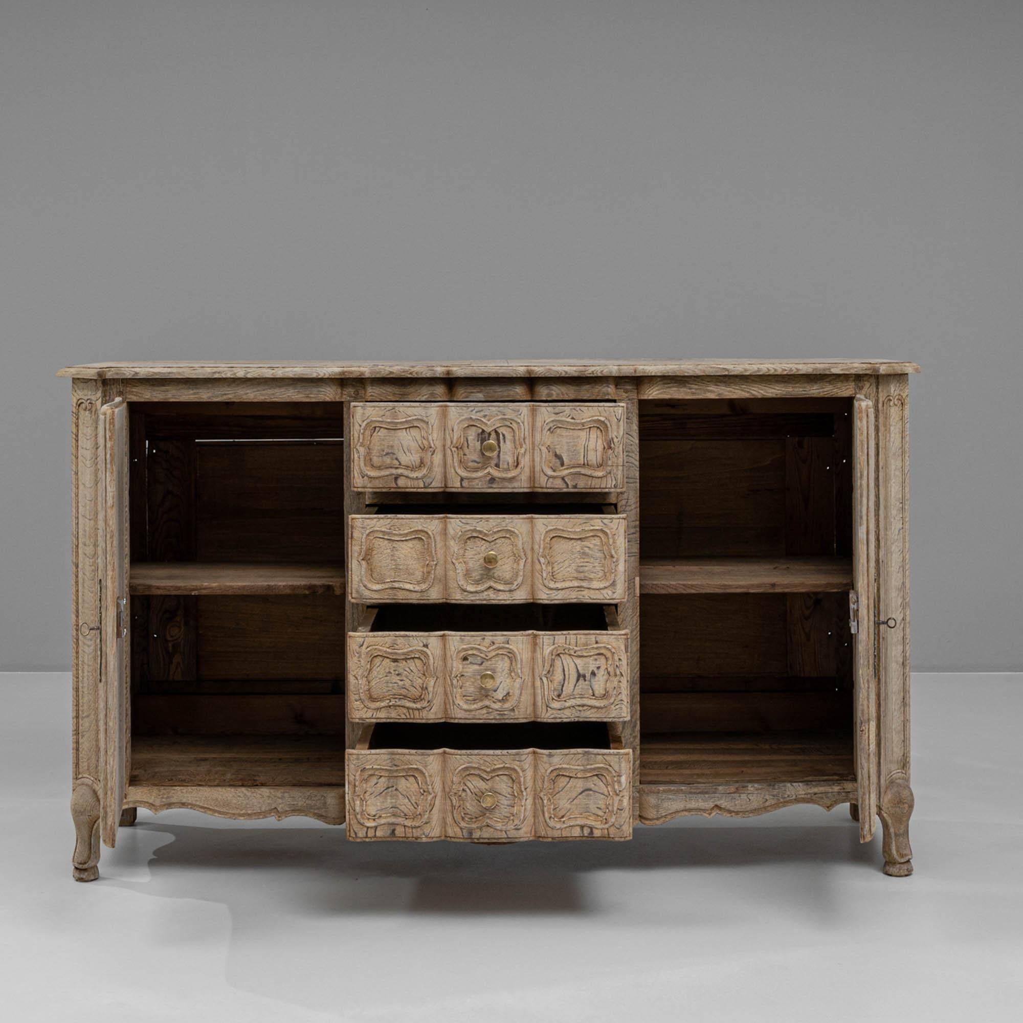 This exquisite 1900s French bleached oak buffet brings a timeless elegance to any room with its beautifully carved details and rustic charm. Crafted from solid oak, the buffet showcases intricate floral motifs and ornate paneling on its double