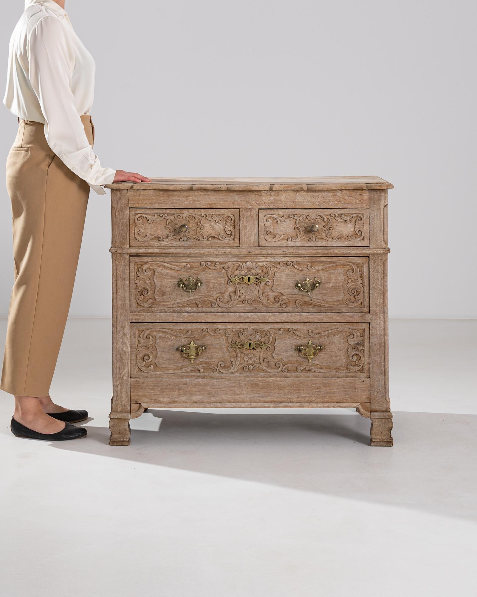 This 1900s French chest of drawers exudes a sense of historical charm and elegance. Crafted from bleached oak, the chest features a soft, natural finish that enhances the wood's timeless beauty. Intricately carved detailing adorns each drawer,