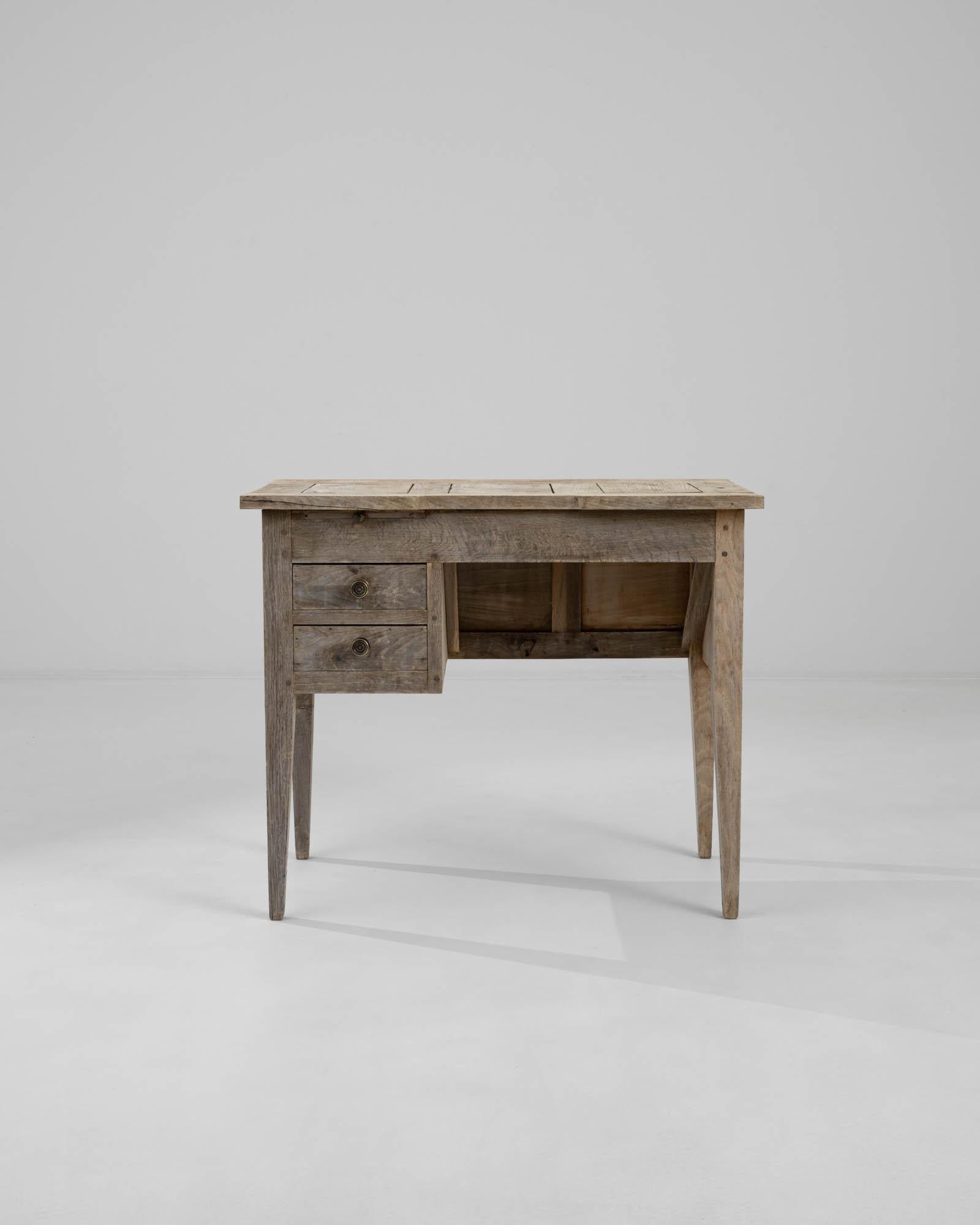A wooden desk created in 1900s France. Neatly composed, highly functional and understated, this petite, oak desk exudes a quiet ornament. A delicate bleaching process has been applied to the surface of the oak, revivifying the natural wood grain and