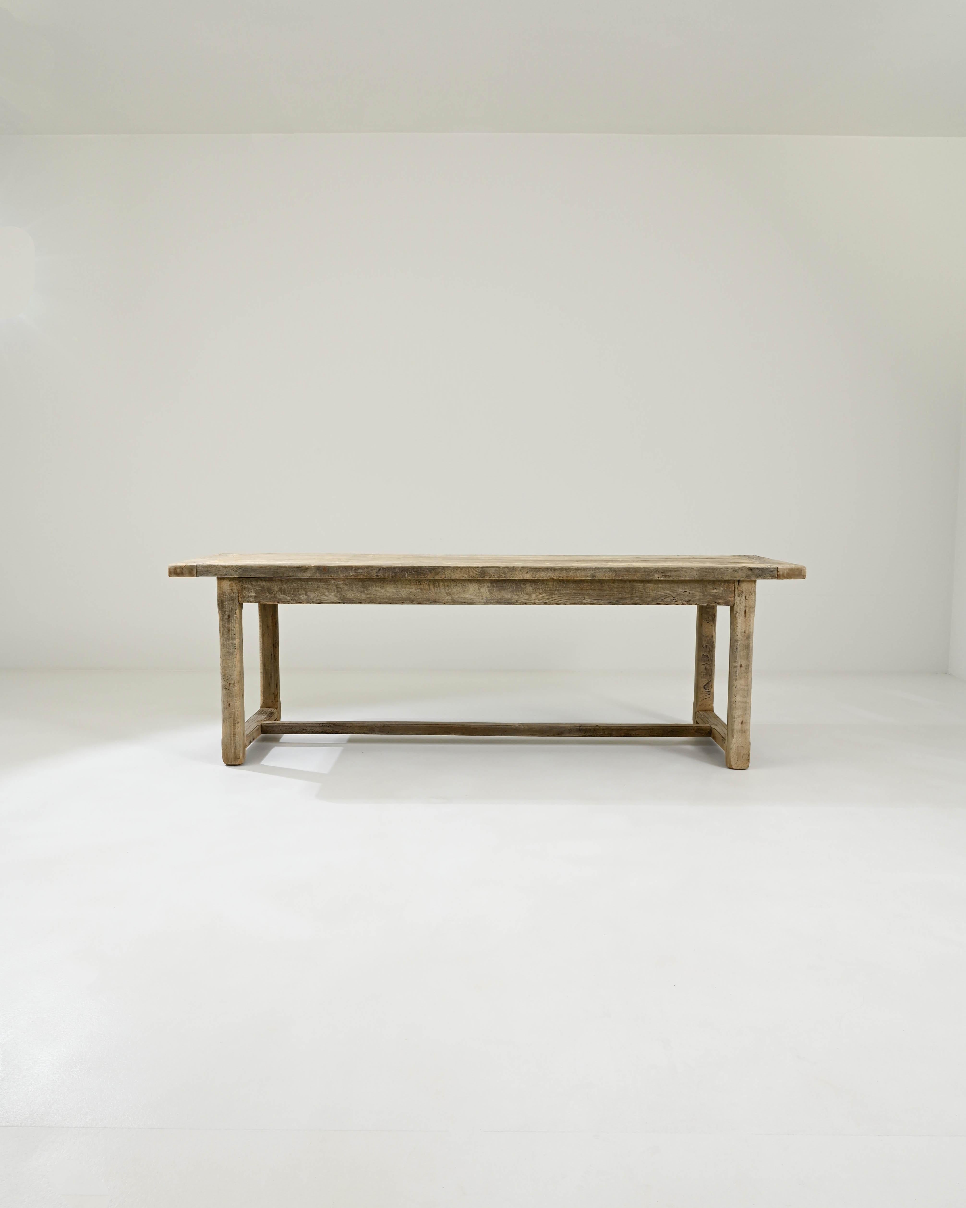 Comfortably accommodating your next dinner party, this table was crafted circa 1900 in France from high-quality European oak. It boasts a long tabletop supported by legs connected to each other by stretchers, forming square structures that add