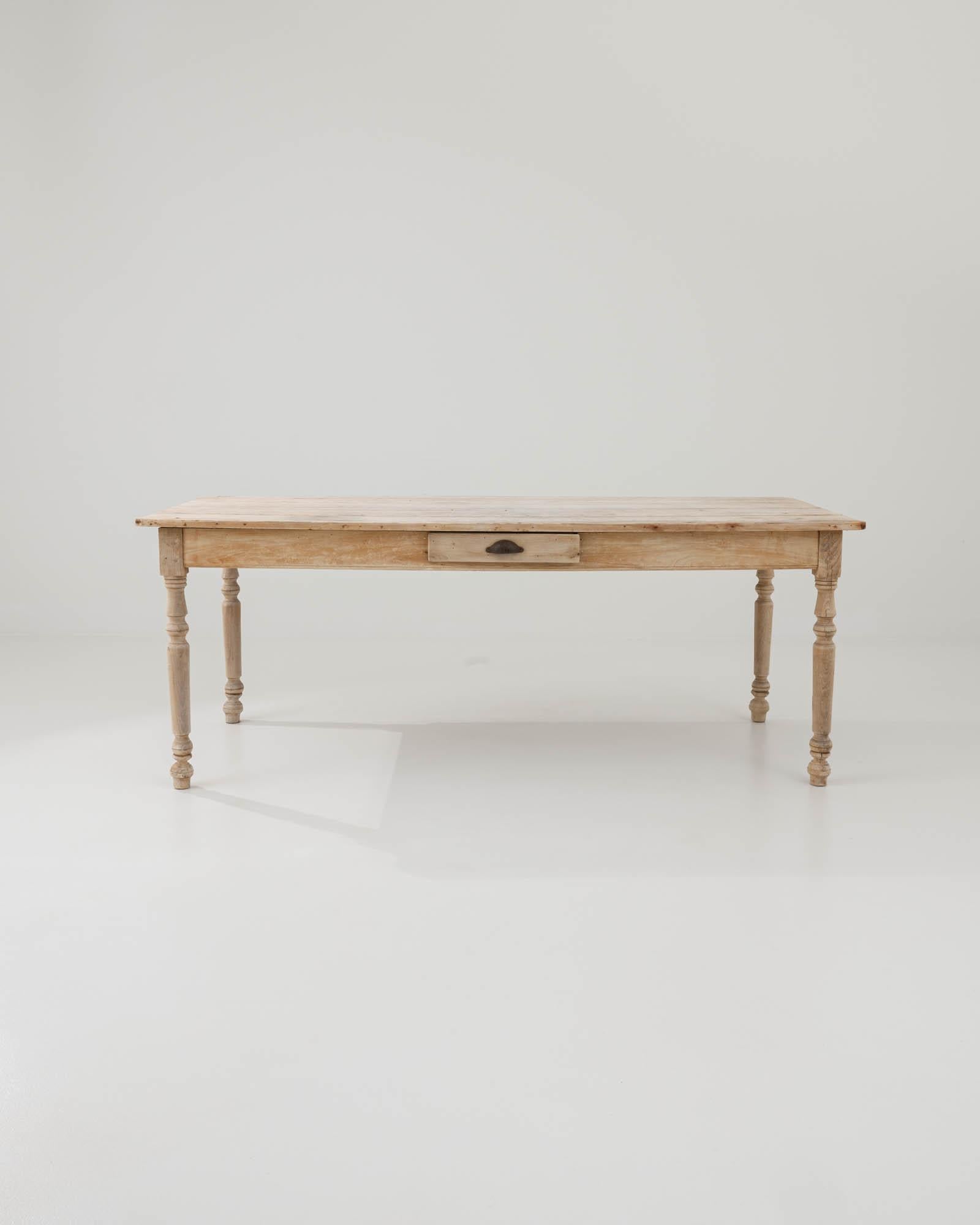 Introducing the 1900s French Bleached Oak Dining Table, a timeless piece bringing a slice of vintage charm into your dining space. Crafted from rich, bleached oak, this table exudes rustic elegance with its classic turned legs and the patina that