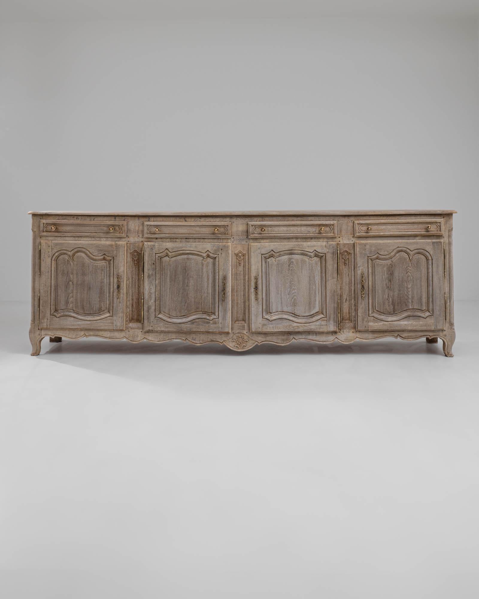 A wooden buffet created in 1900s France. This expansive buffet stretches outward inviting one to place their valuables within its treasured storage space. Composed with four spacious doors and drawers, this stylish piece offers ample function in