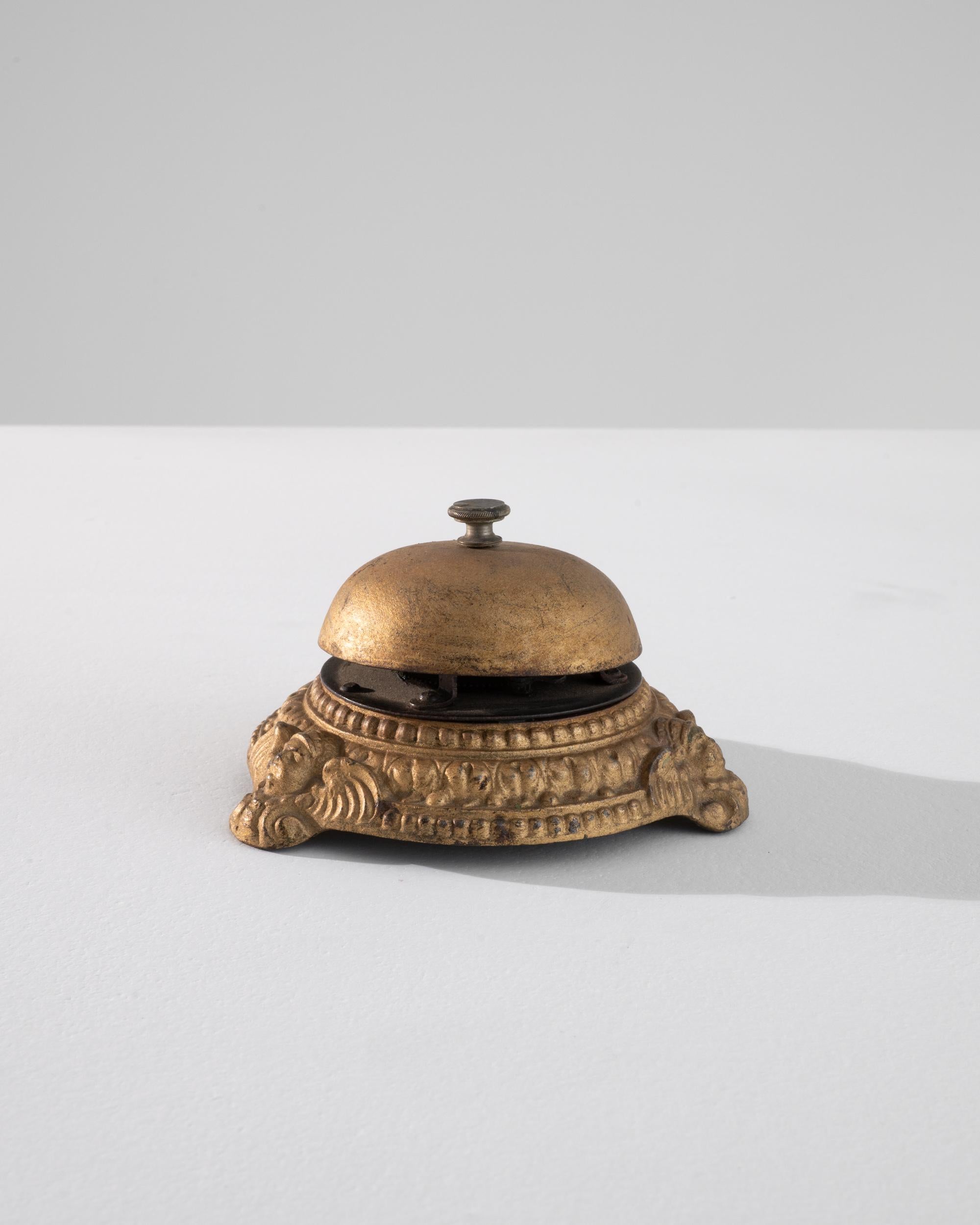 A brass bell created in 1900s France. Small, but immediately noticeable, this brass call bell makes a loud impression even when silent. An impressively detailed, cast pattern runs its circumference, punctuated by angelic faces wreathed in feathers.
