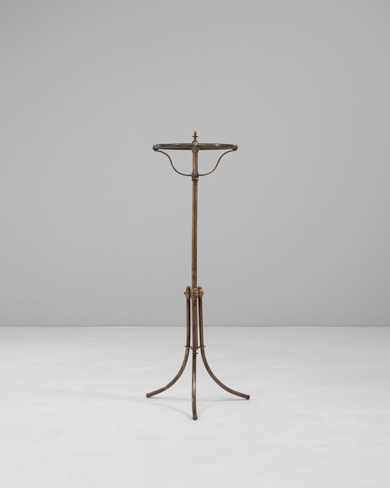 Questo appendiabiti da terra in ottone francese del 1900 presenta una silhouette architettonica distintiva che riflette l'elegante utilità del design di fine secolo. Realizzato in ottone patinato, poggia su quattro gambe delicatamente ricurve che si