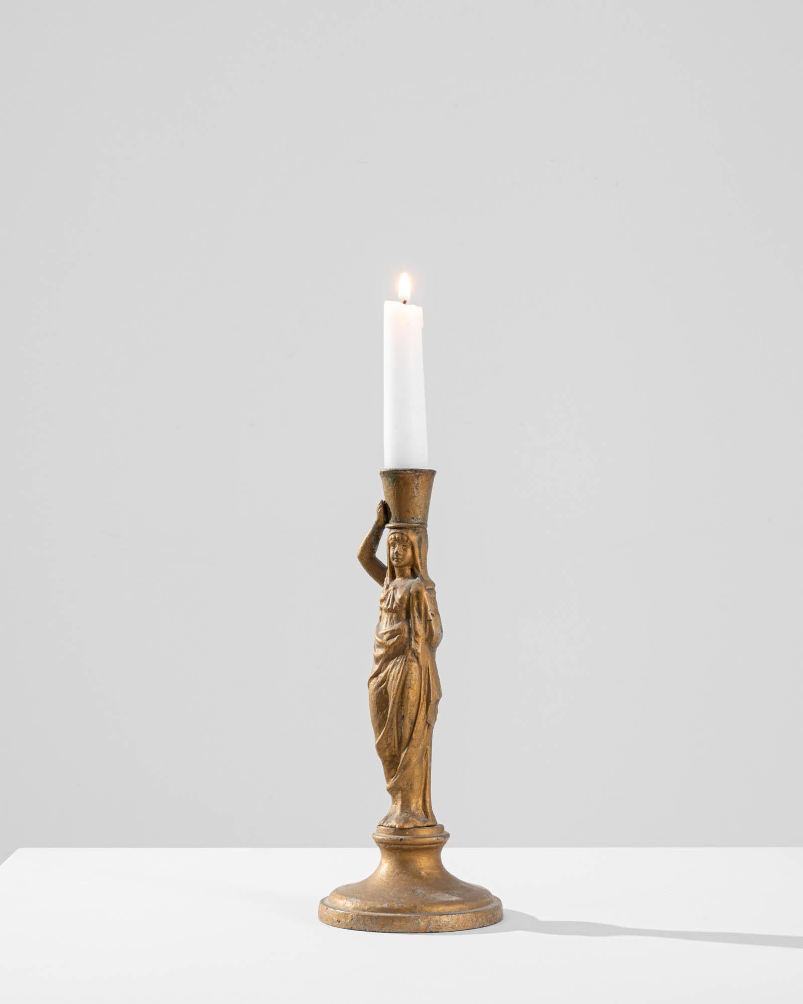 Embrace the grace and elegance of this 1900s French Brass Woman Candlestick. Crafted from brass, this candlestick features a stunning depiction of a woman standing on a pedestal with remarkable poise. She carries a water bucket atop her head,