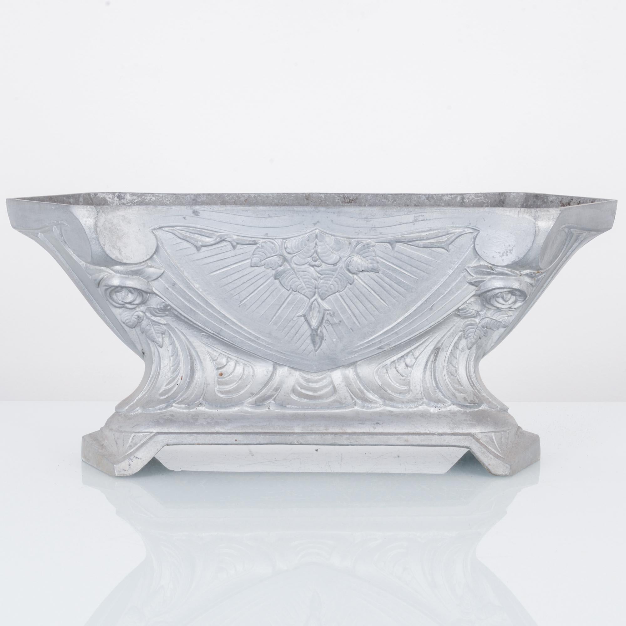 This cast aluminum planter was made in France, circa 1900. The details on its base and the elaborate design of flowers and leaves on its body give it a touch of elegance. The planter has a tapered body, widening toward the base. It displays a