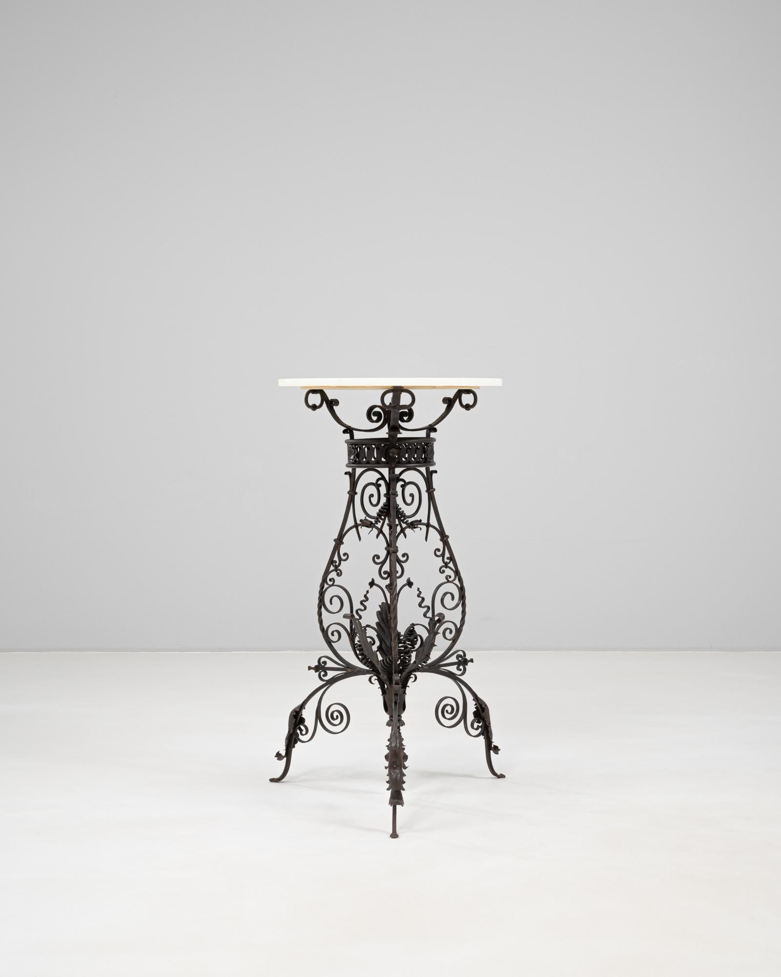 This 1900s French cast iron side table features an ornate wrought base with scrolling foliate motifs and a rich blackened patina, embodying the decorative spirit of the Belle Époque era. The base is beautifully detailed with acanthus leaves,
