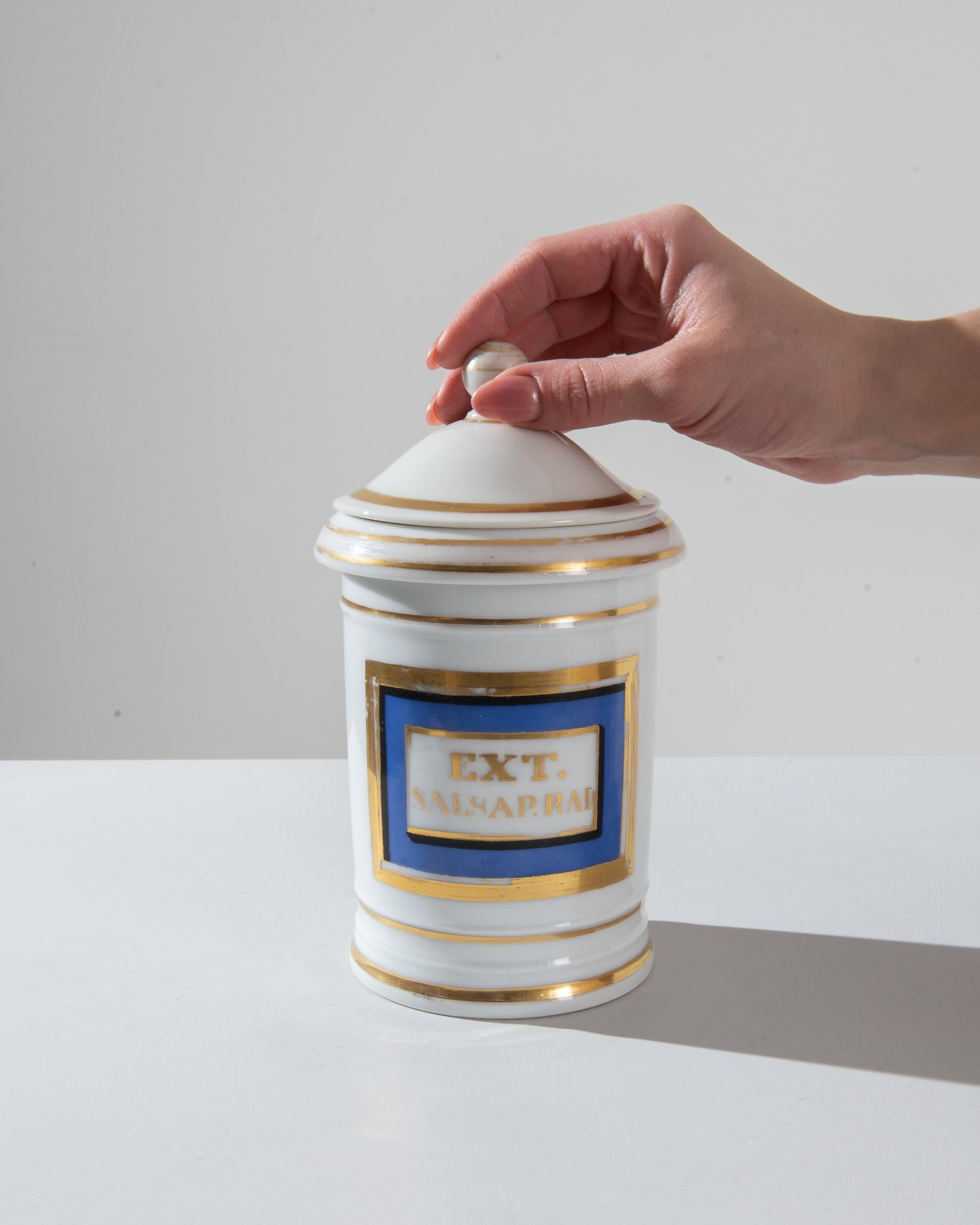 Add a touch of vintage elegance to your space with this 1900s French Ceramic Jar. The jar, with its pristine white base and delicate gold accent lines, exudes a sense of sophistication. The middle section, adorned in a calming blue hue, features