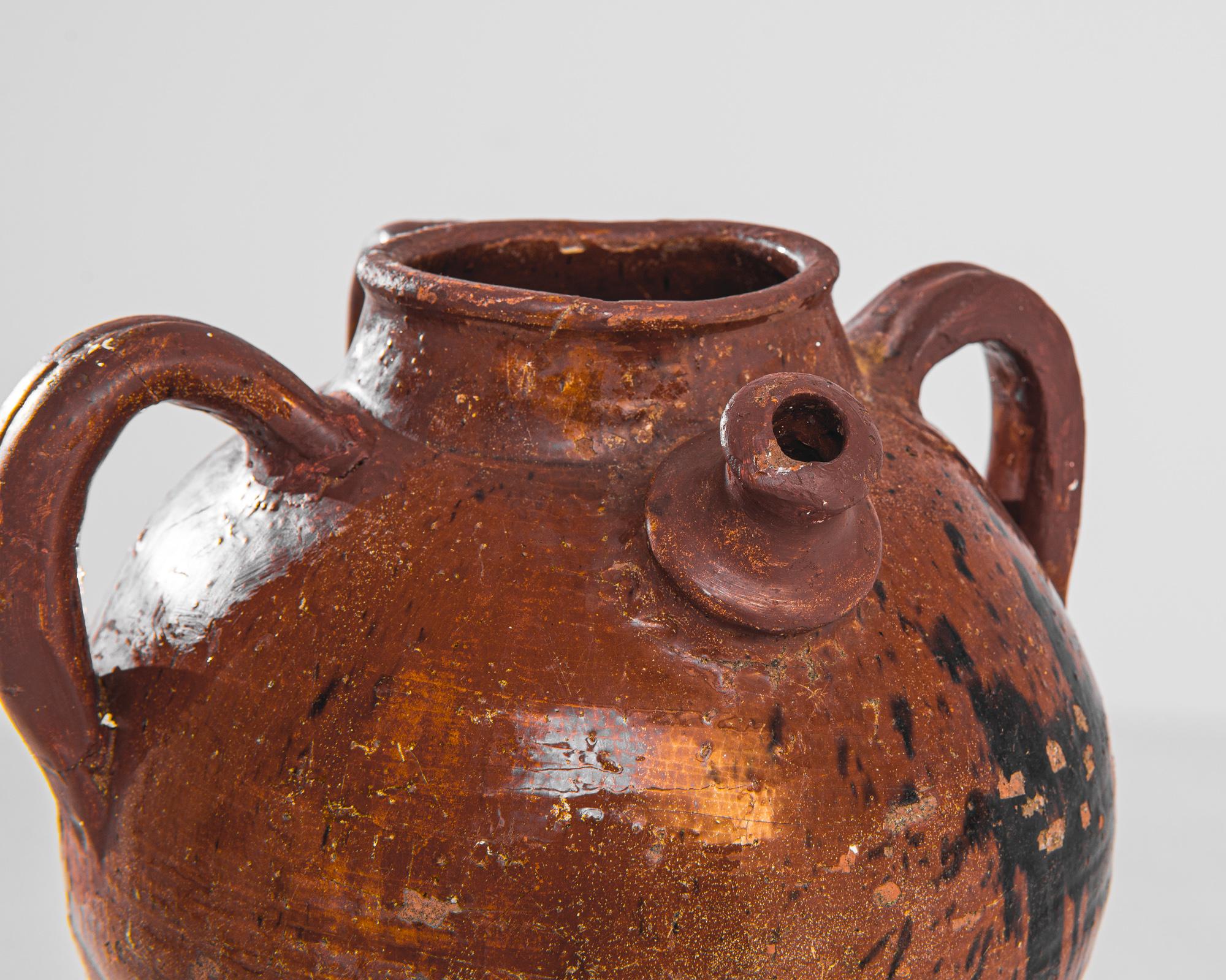 Fai un salto indietro nel tempo con questa autentica brocca in ceramica francese del 1900, testimonianza della vita pastorale e della ceramica tradizionale. I toni caldi e terrosi del corpo in terracotta sono completati dalla patina scura, che