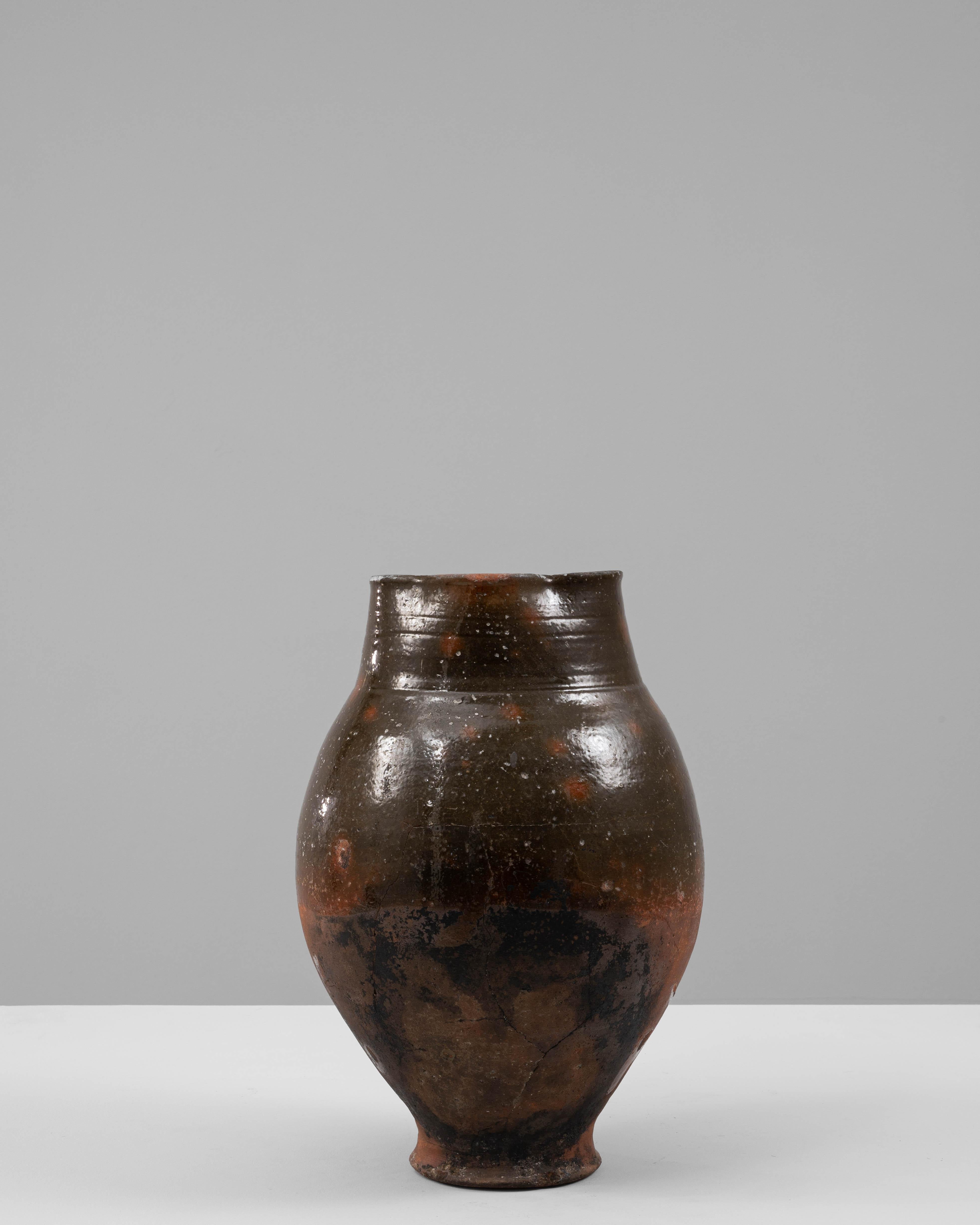 Questa brocca in ceramica francese del 1900 mostra il fascino rustico e la qualità artigianale caratteristici delle ceramiche dell'inizio del XX secolo. La forma allungata e bulbosa è rifinita con uno smalto ricco e terroso nei toni del marrone
