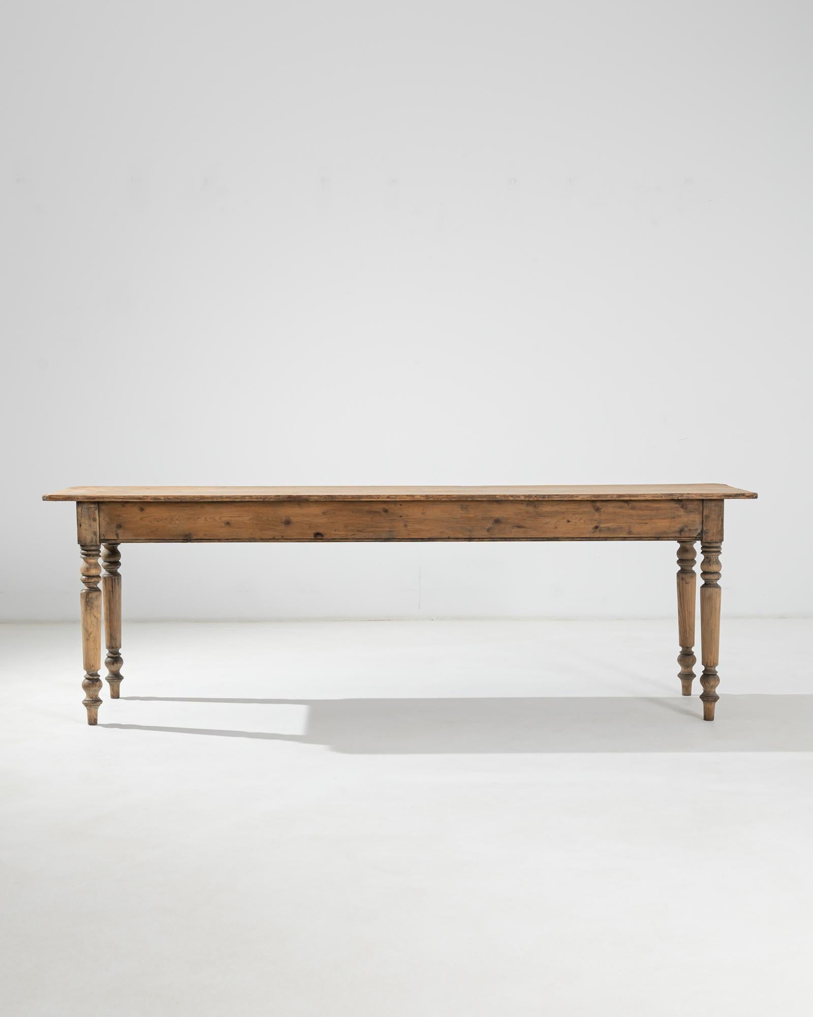 A wooden console table made in France circa 1900. Elevated on masterfully carved baluster legs, the long, narrow table top plays with the distorted sense of proportion, adding an extravagant counterpoint to the table’s rustic allure.