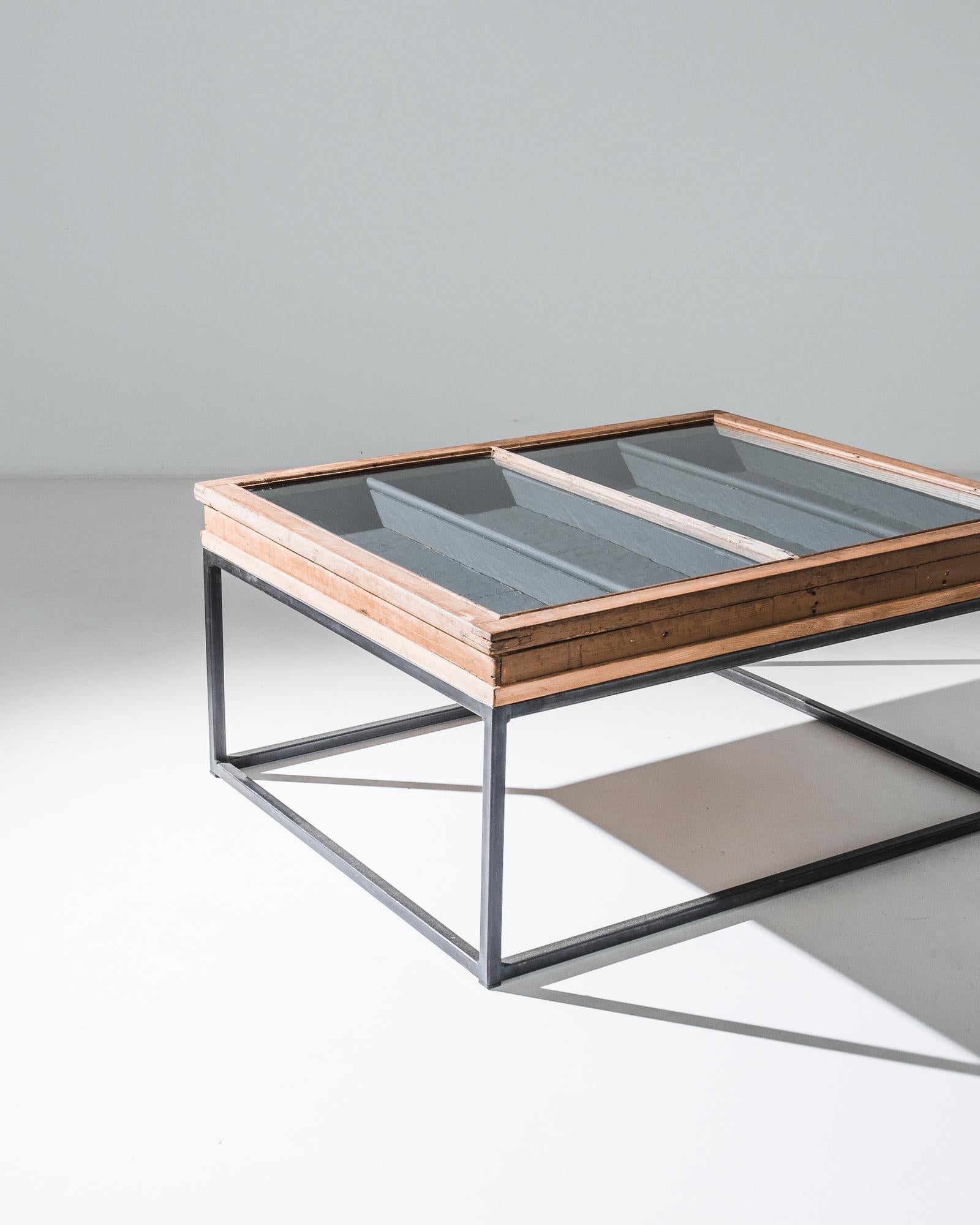 A metal coffee table with glass and wood tabletop from France, produced circa 1900, has been fitted with a metal base in our atelier. Nestled neatly between categories of coffee table and shadow box, this unique antique features a glass top box of