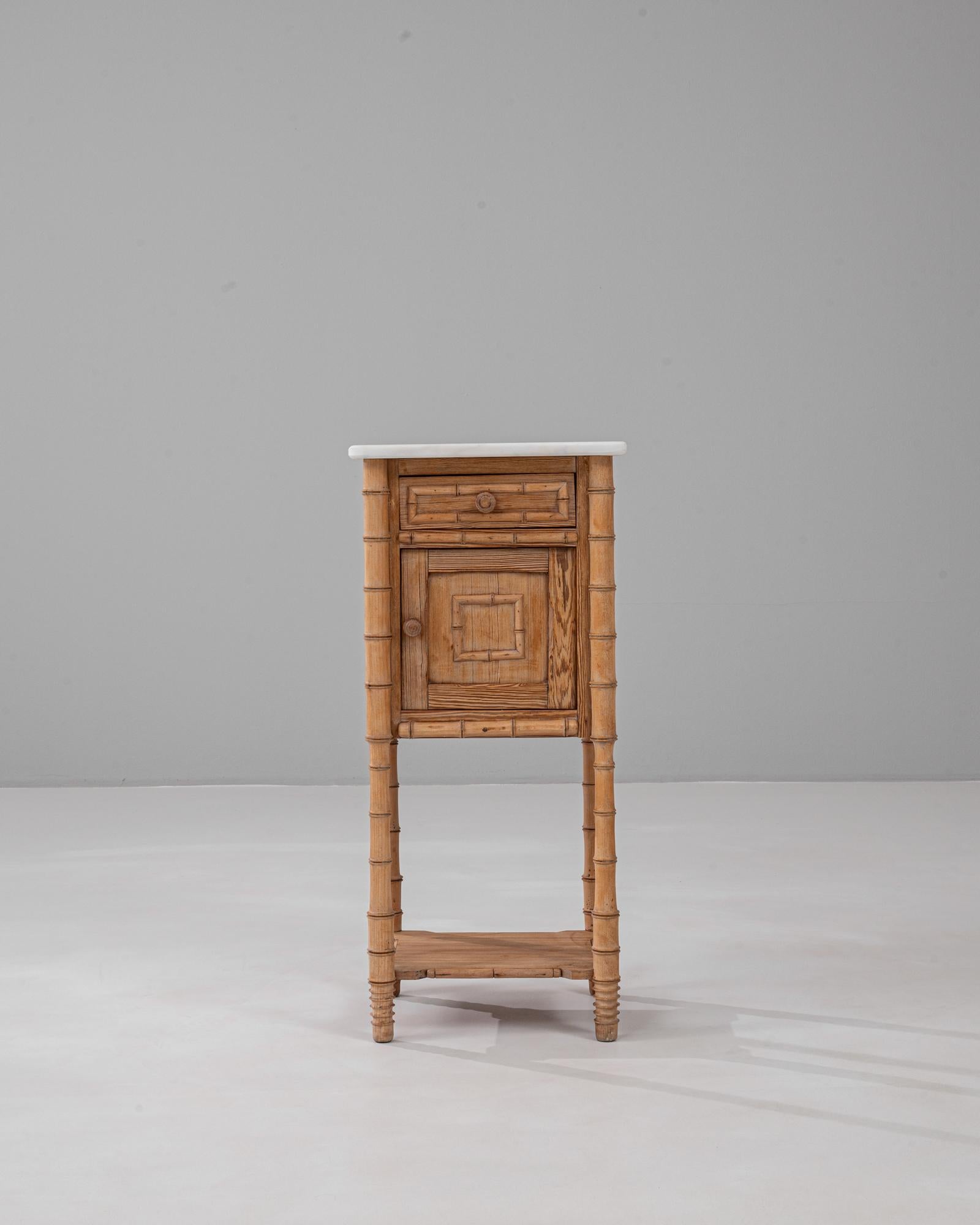 Esta mesilla de noche francesa de bambú sintético de 1900 captura el encanto y la artesanía de la época de la Belle Époque. El marco, tallado para asemejarse al bambú, muestra delicados detalles y una cálida madera de tono miel. Una encimera de
