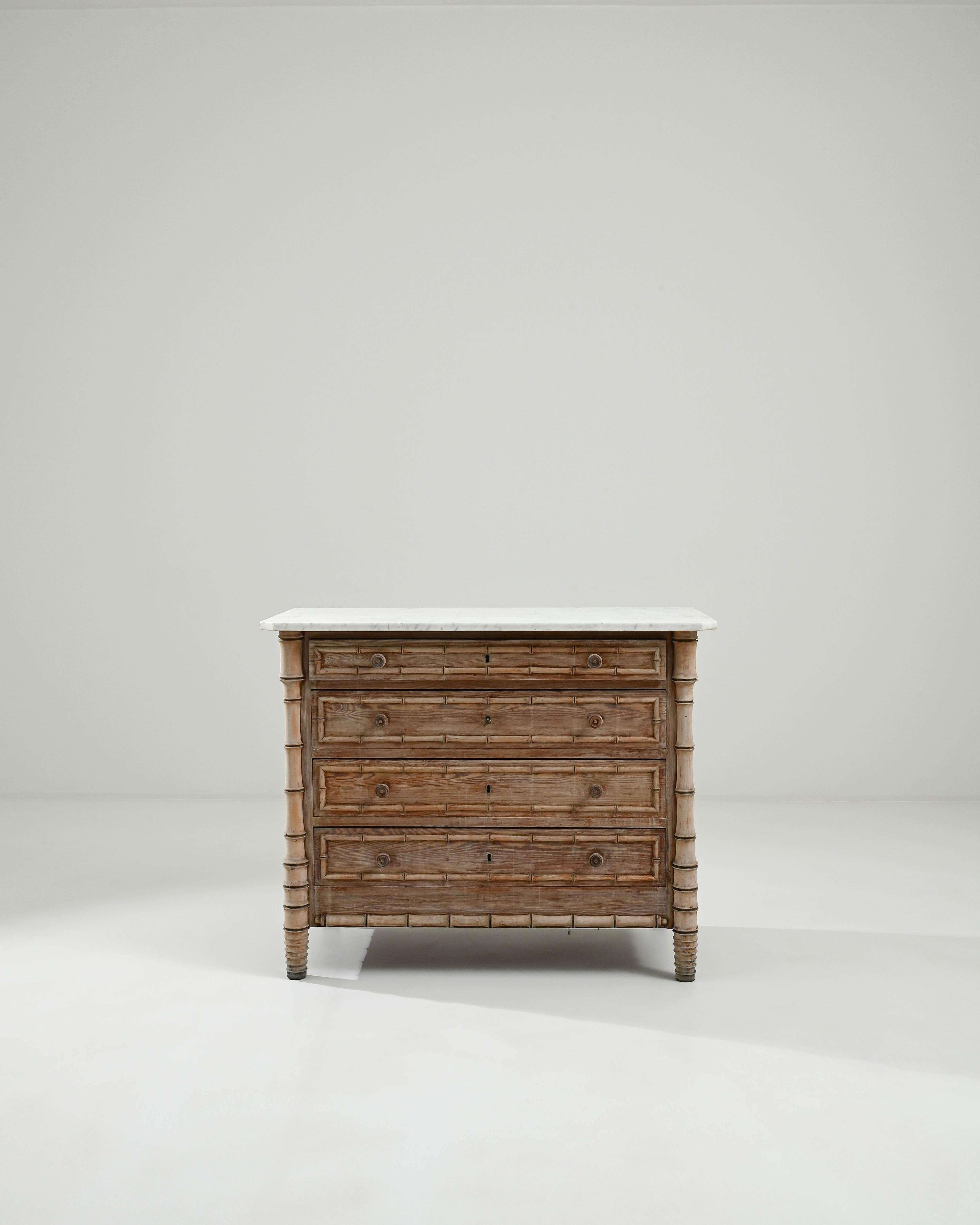 A wooden chest of drawers created in France circa 1900. This chest of drawers is composed with wood carved into the shape of bamboo, outlining the drawer faces and forming the legs. Adding a fresh light to this unearthed treasure, the white marble