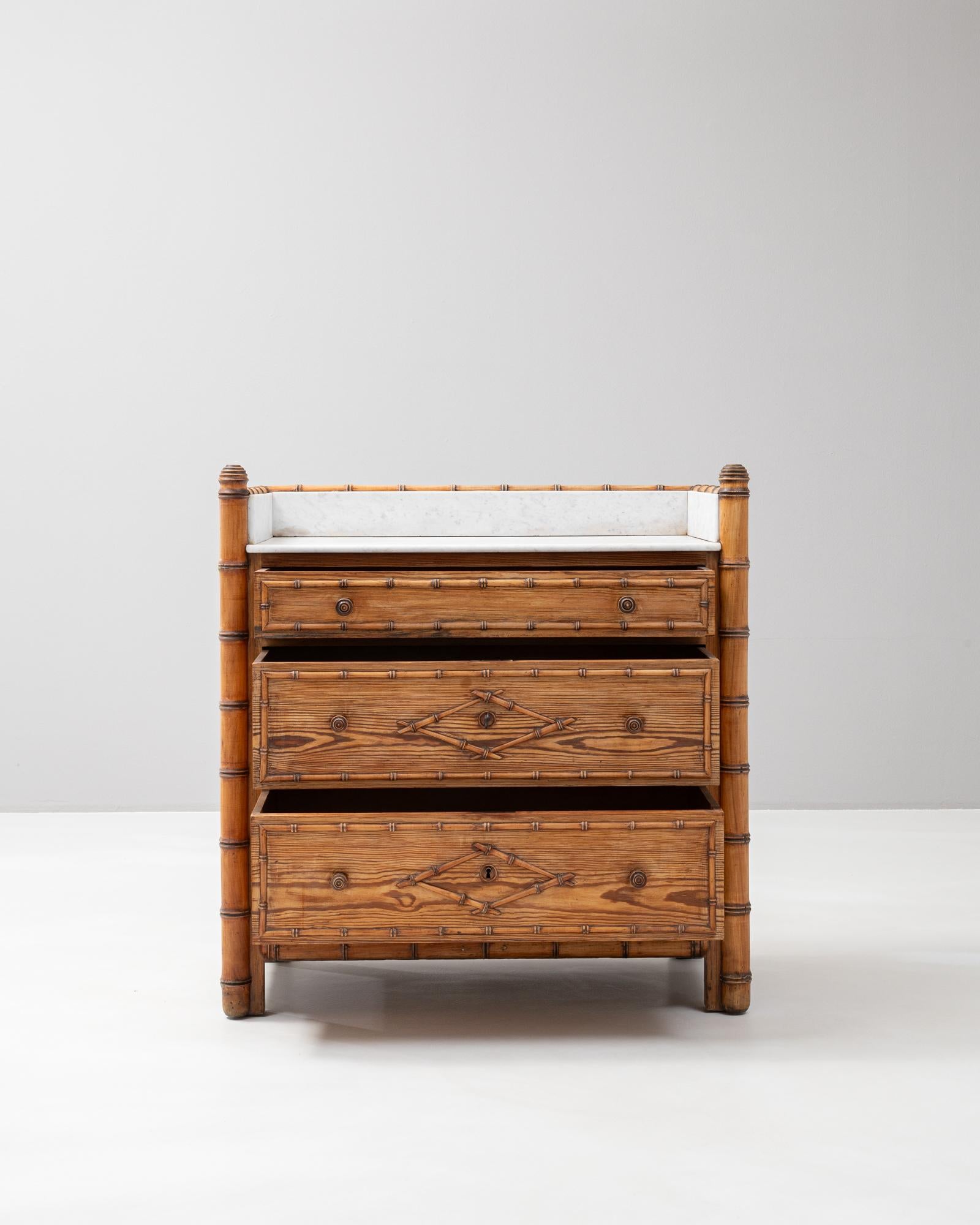 This 1900s French faux bamboo chest of drawers is a charming blend of craftsmanship and design. Featuring a marble top framed by a low gallery, it combines functionality with elegant materials. The wooden frame is intricately carved to resemble