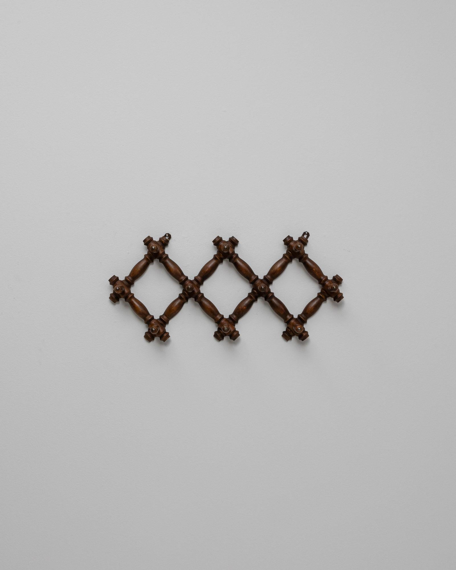 This 1900s French wall hanger features a charming faux bamboo design crafted from richly stained wood. The expandable accordion form combines function with decorative appeal, allowing the piece to be adjusted in width to suit various spaces. Turned