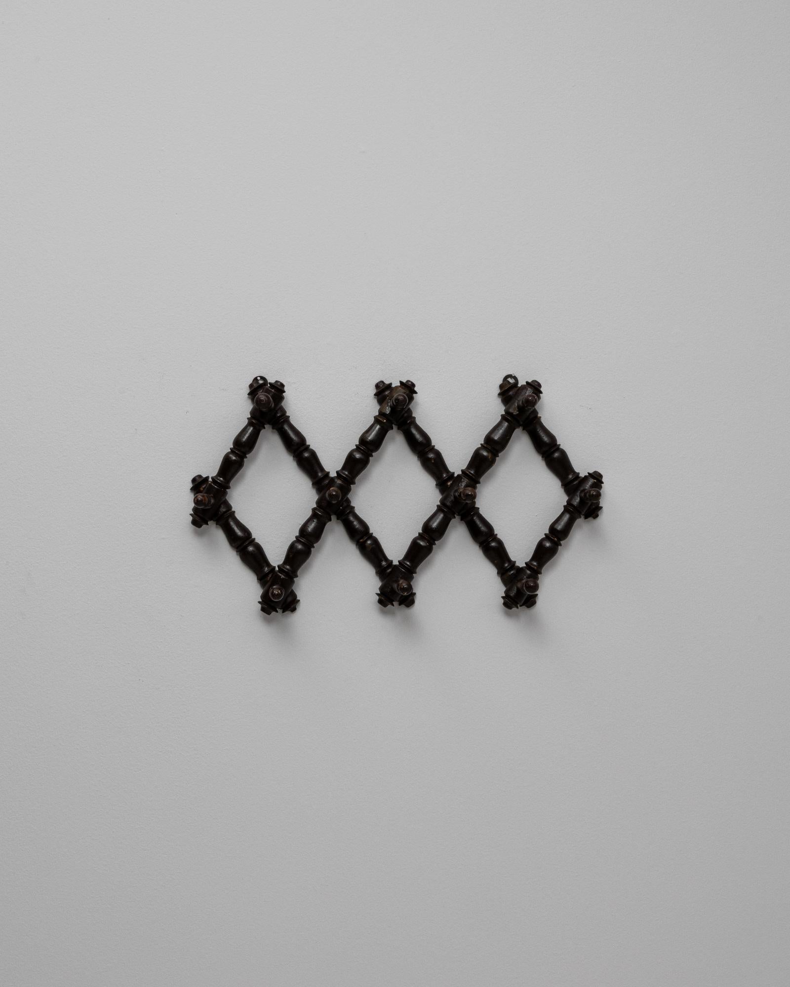 This 1900s French wall hanger features a charming faux bamboo design crafted from richly stained wood. The expandable accordion form combines function with decorative appeal, allowing the piece to be adjusted in width to suit various spaces. Turned