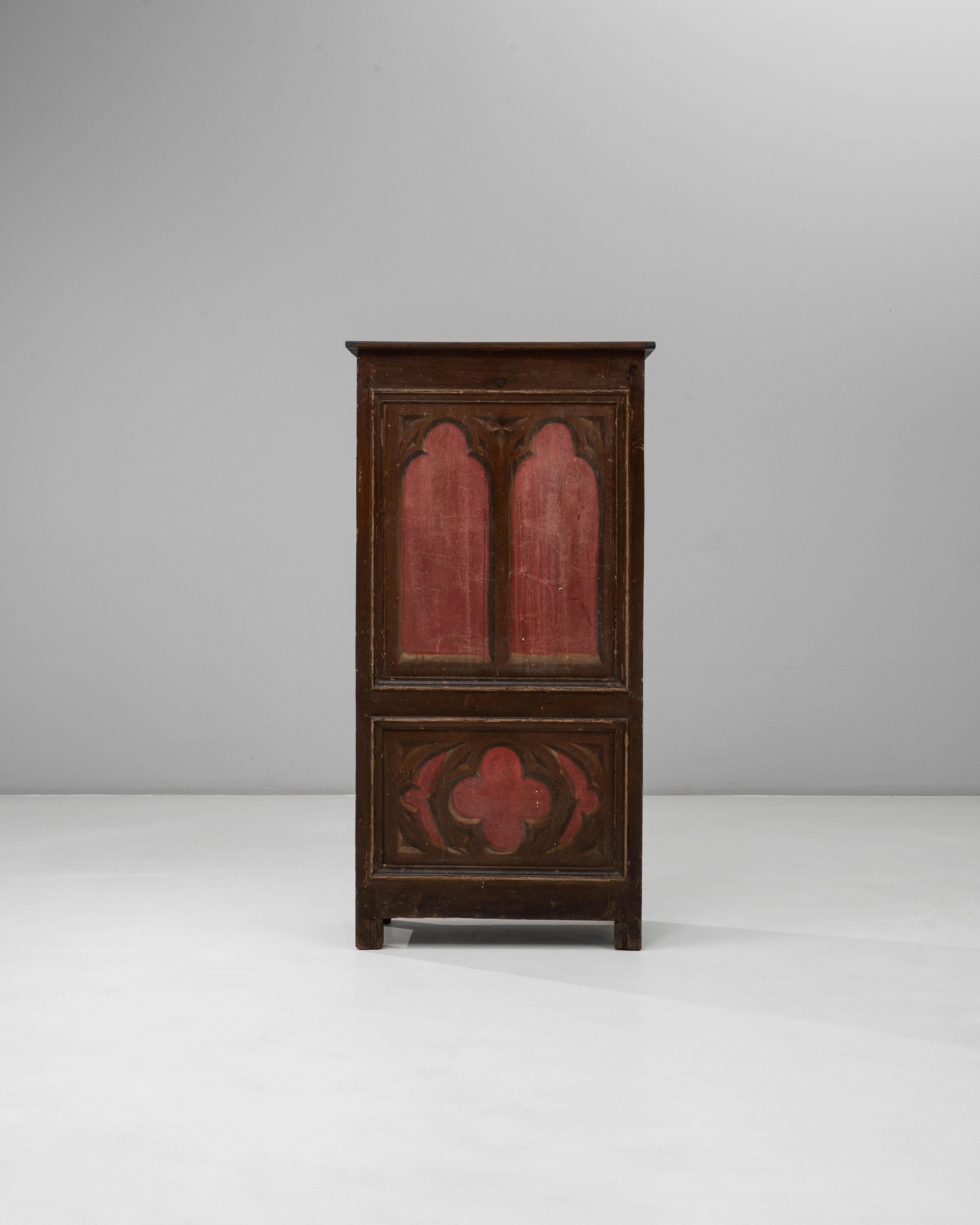 Questo mobile dipinto del 1900 in stile Gothic Revival francese è caratterizzato da sorprendenti motivi architettonici che richiamano la grandezza del design medievale. I pannelli frontali mostrano alte forme ad arco sopra un medaglione a