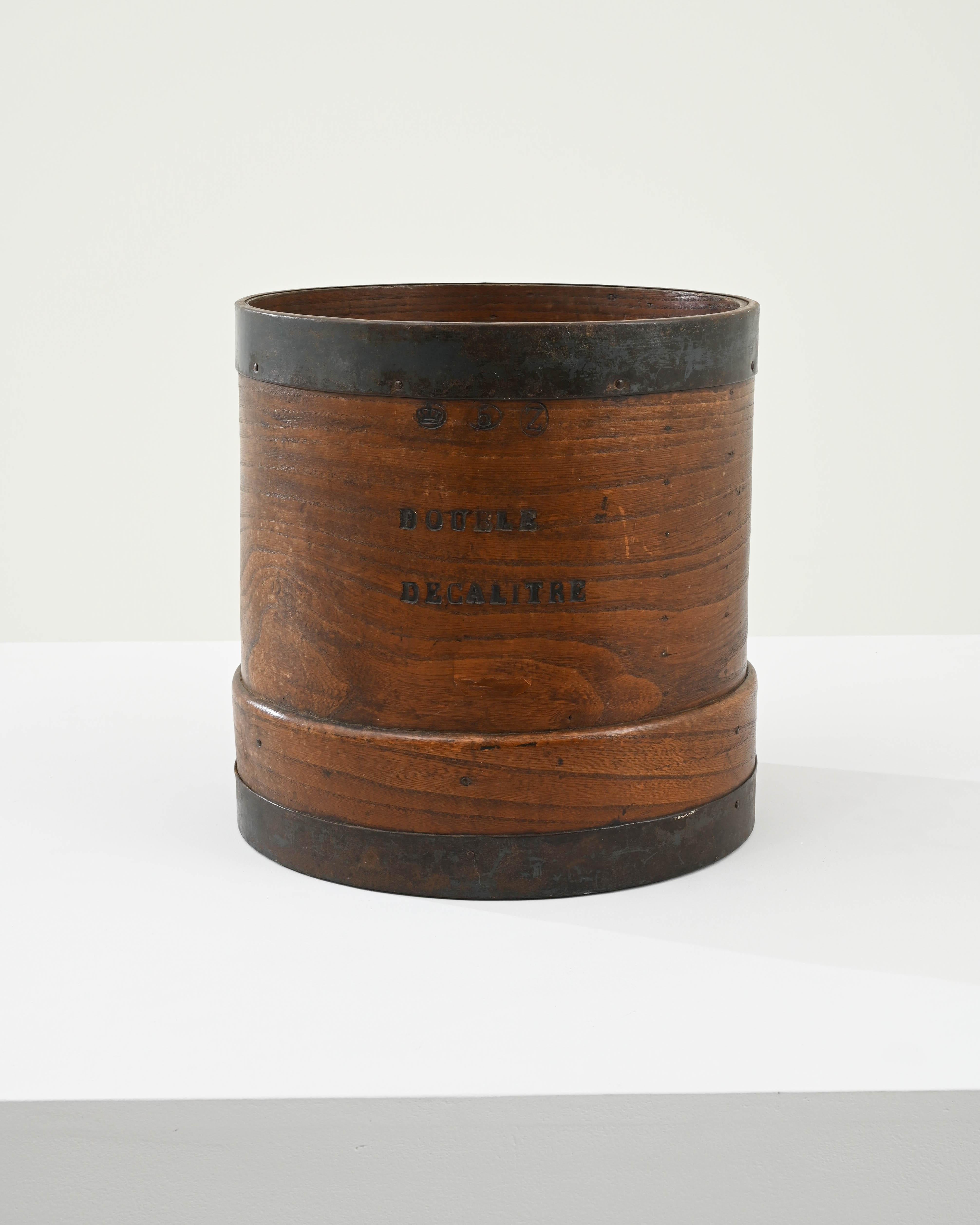 A wooden and metal bucket originating in France, circa 1900. Originally used for measuring out volumetric units of dry goods in stores or markets, stamped and approved with certainty, ‘double decalitre’ as indicated, faithfully measures 20 liters