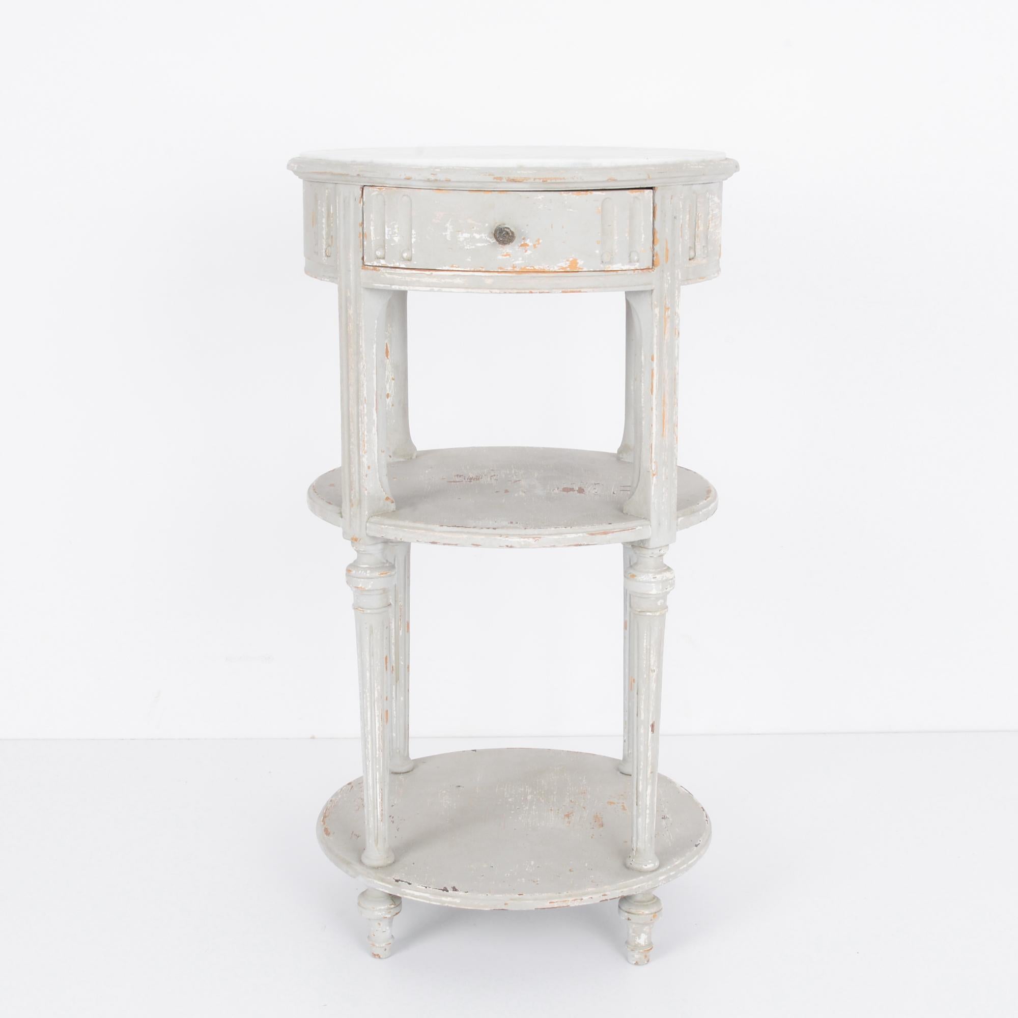 A vintage wood patinated table with marble top from France, circa 1900. Three-tiered table with sliding drawer. Fluted legs give this table an architectural aspect something like a bell tower waiting for its bell. A side table of a mover-shaker, a