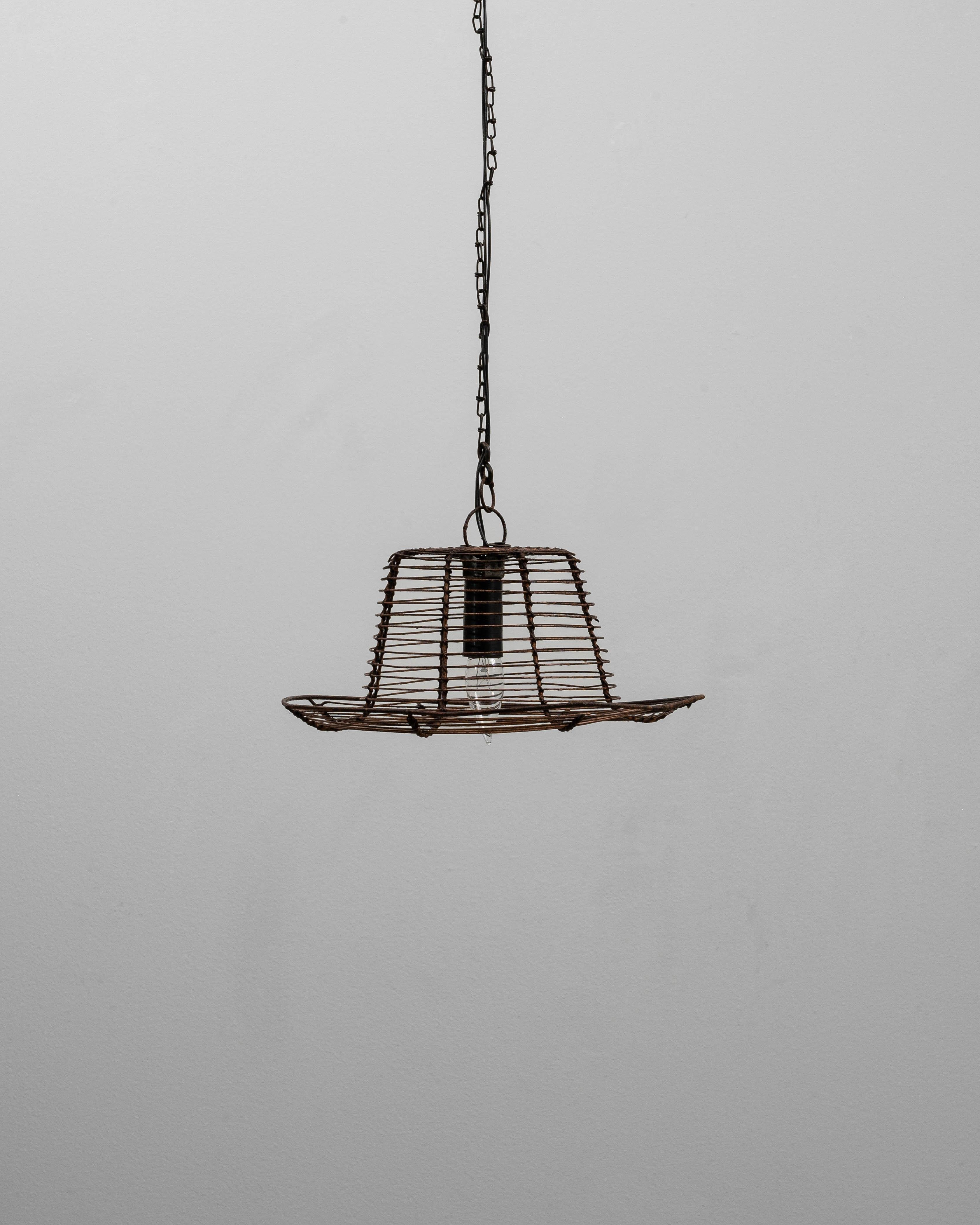 Questa lampada a sospensione industriale francese a cornice metallica svasata del 1900 riflette l'ingegnosità utilitaristica dell'illuminazione delle officine e delle fabbriche. Realizzato in filo metallico delicatamente piegato, il paralume forma