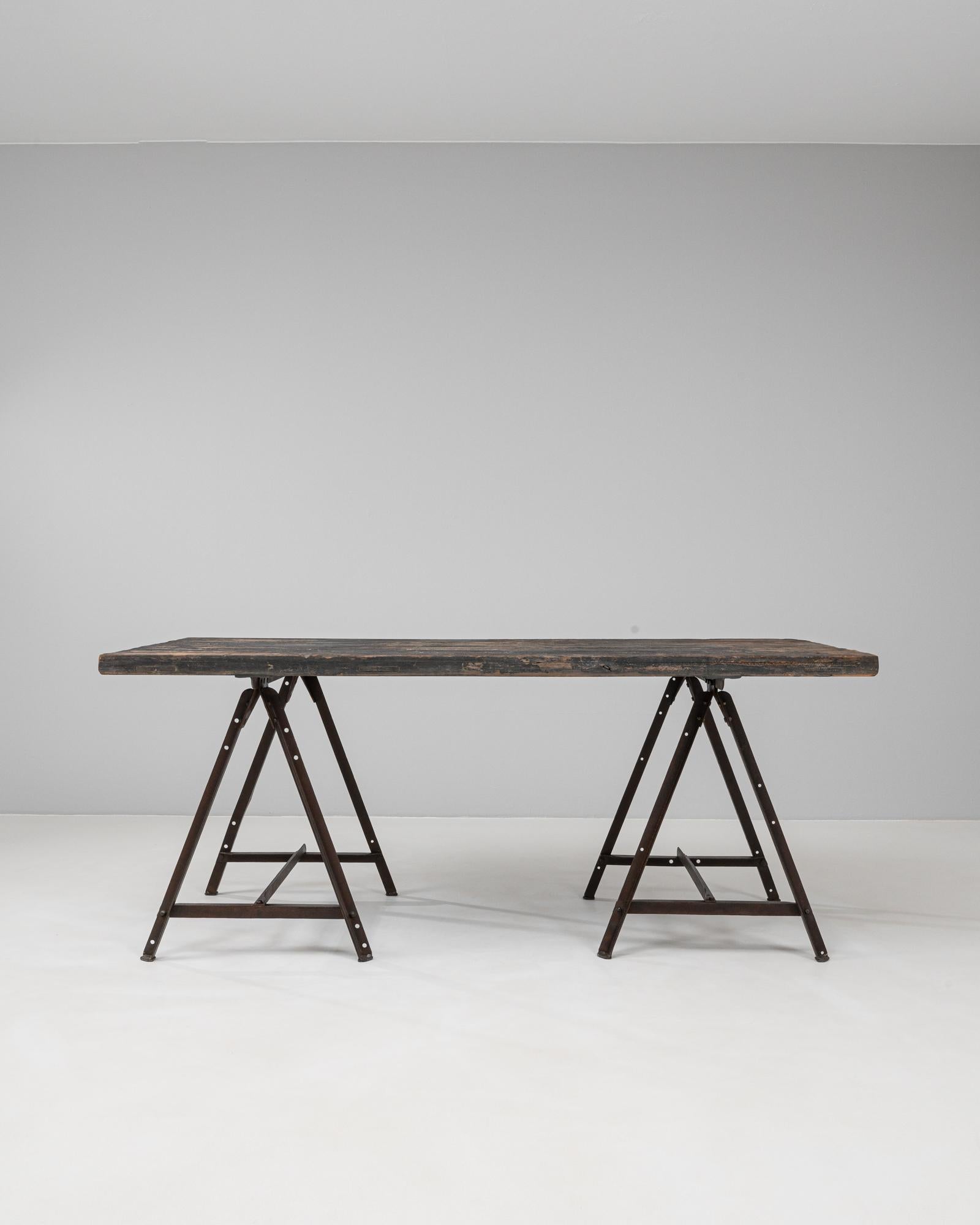 Table industrielle française des années 1900. Cette table de style établi du début du XXe siècle capture le caractère utilitaire du design industriel français avec ses matériaux robustes et sa forme fonctionnelle. La base du tréteau en fer sombre