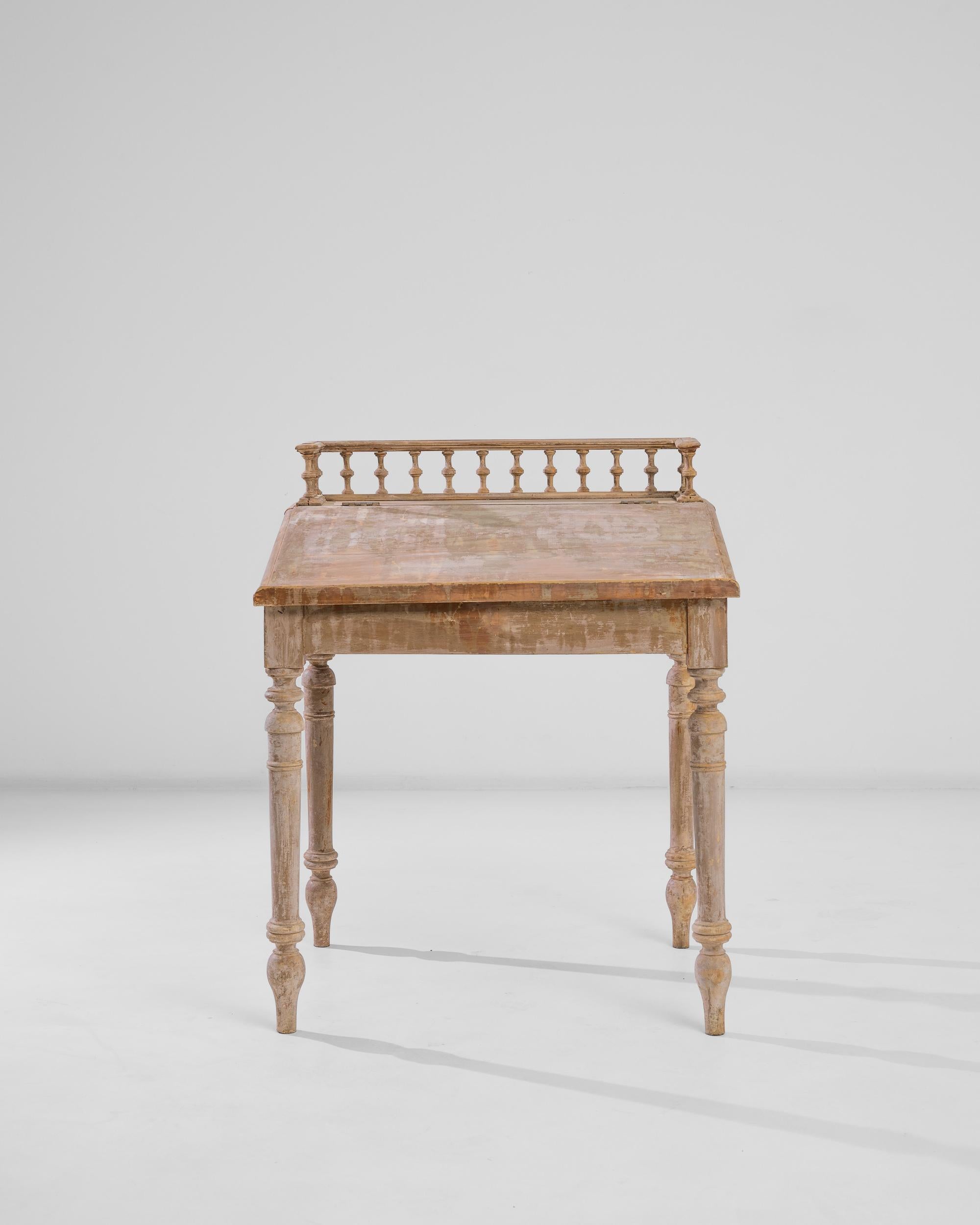 An antique writing desk from France, produced during the turn of the century. An elegant lift-top provides a practical sloping writing surface, crowned with a wooden gallery rail. Perched on ring turned legs with turnip feet, the lid can be lifted