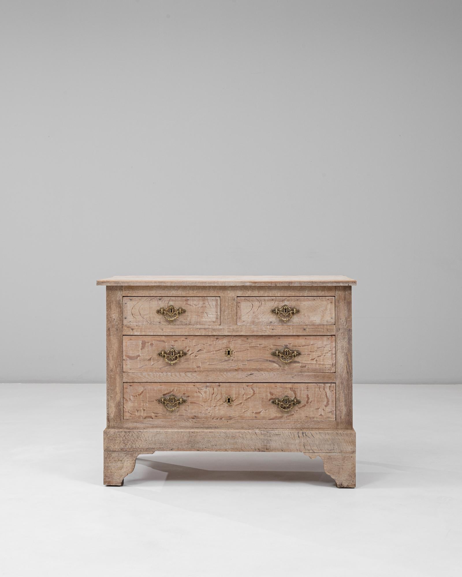 This 1900s French Louis XVI chest of drawers showcases classic neoclassical symmetry and understated refinement. Crafted from oak with a softly bleached finish, the piece highlights the natural grain and texture of the wood. Its four drawers feature
