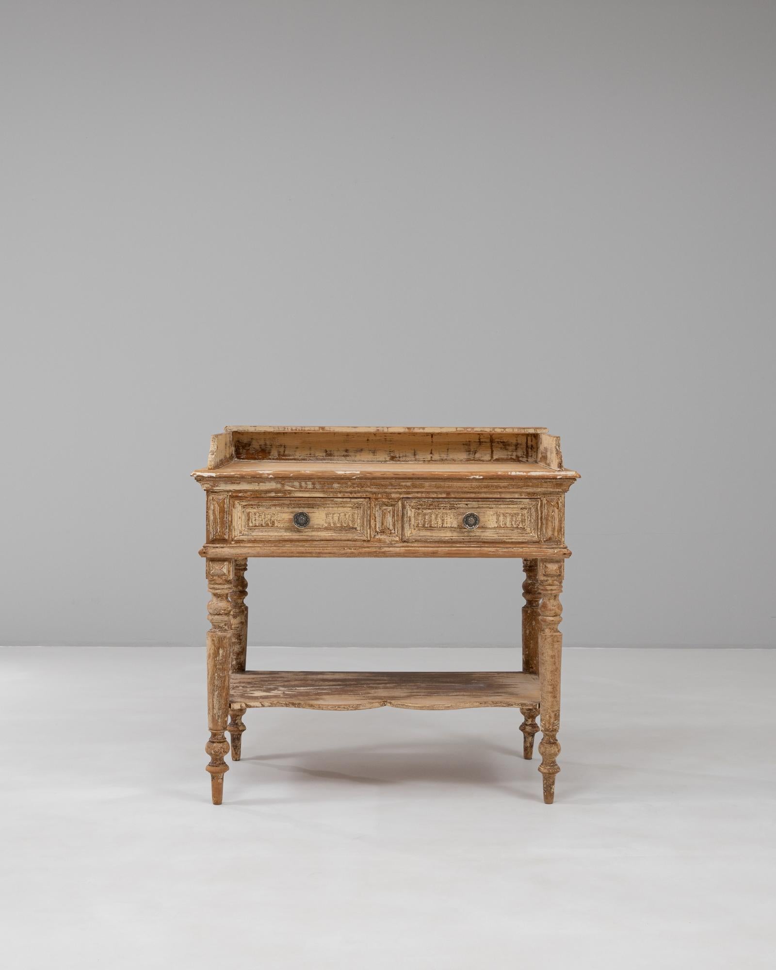 This 1900s French Louis XVI wood patinated console table embodies classical elegance with a rustic finish that highlights its age and authenticity. Crafted from solid wood, the table features turned and fluted legs characteristic of the Louis XVI
