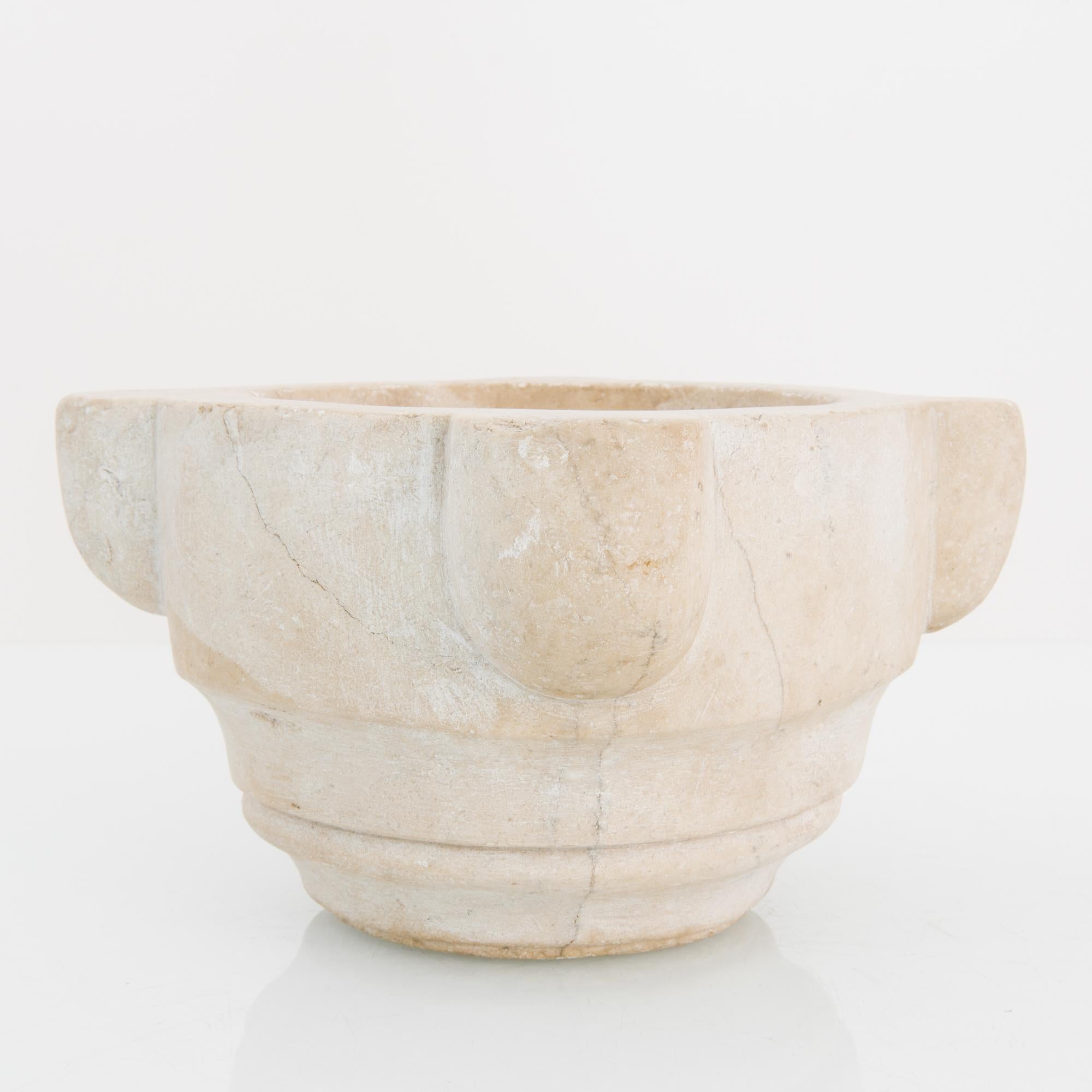 A stone mortar from France, circa 1800. Rustic and refined, the mortar is rendered in cloudy beige marble; the sculpted organic shape giving an effortless shape to hefty marble. The materiality of this timeless antique imparts an immediate tactile