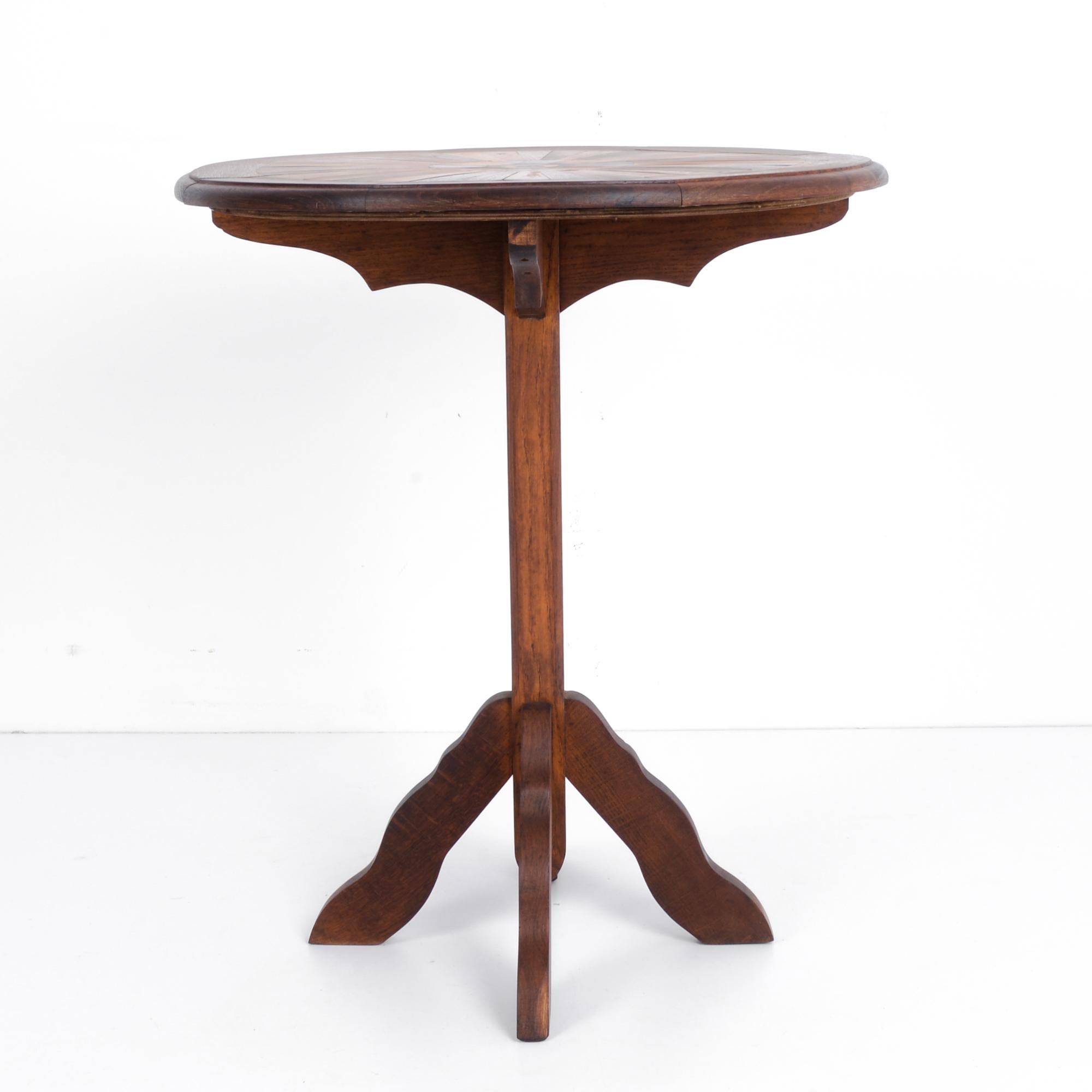 This wooden side table was made in France, circa 1900. A four-legged base around a post supports the table. The round tabletop features a radial arrangement of wooden bars, each displaying an elegant, polished finish. This multi-toned effect from