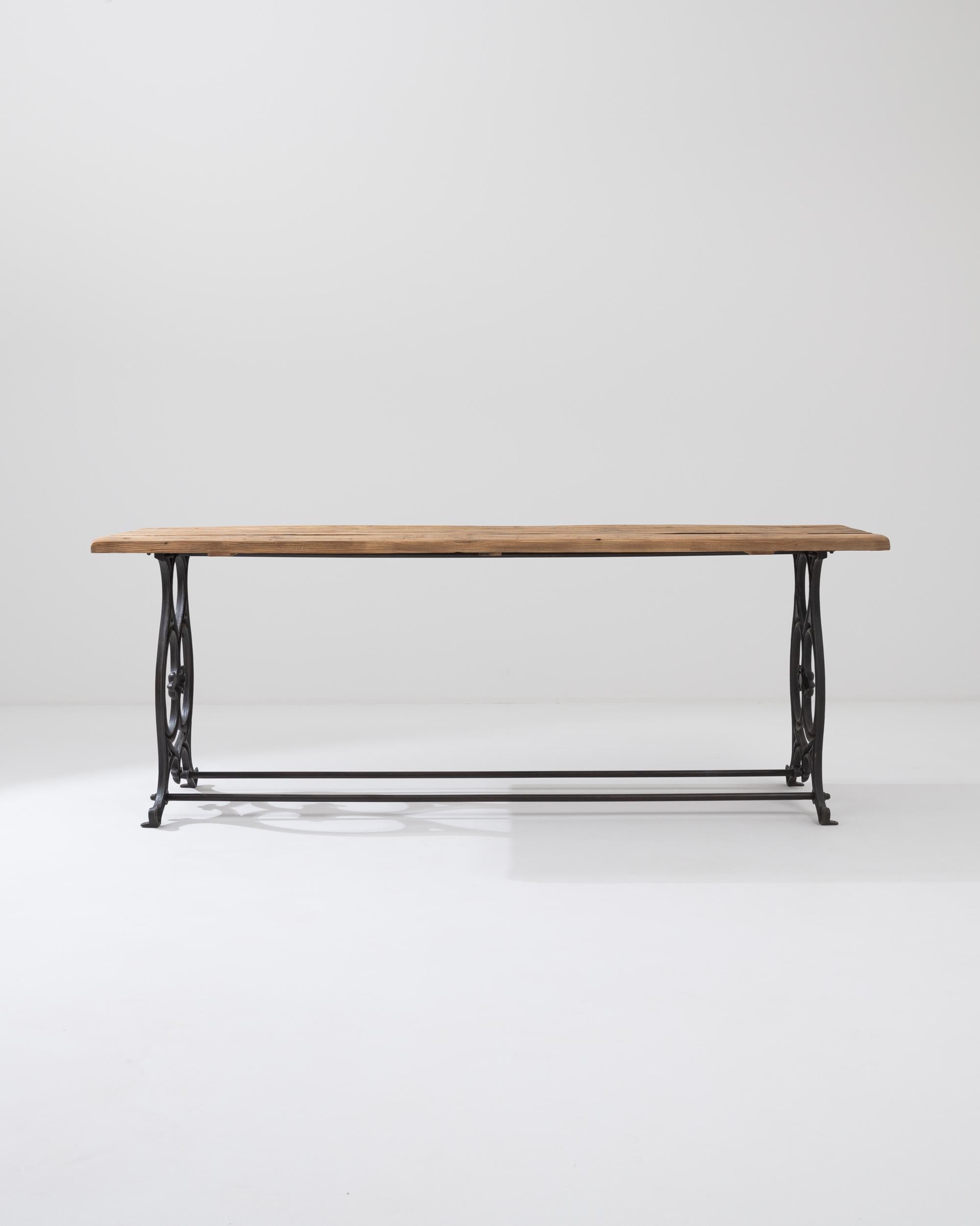 A metal table with a wooden top made in 1900s, France. Gracefully metal legs join together this simple yet elegant table. With three wooden table top slots and a cast understructure, this unique table combines rustic charm with an esteemed