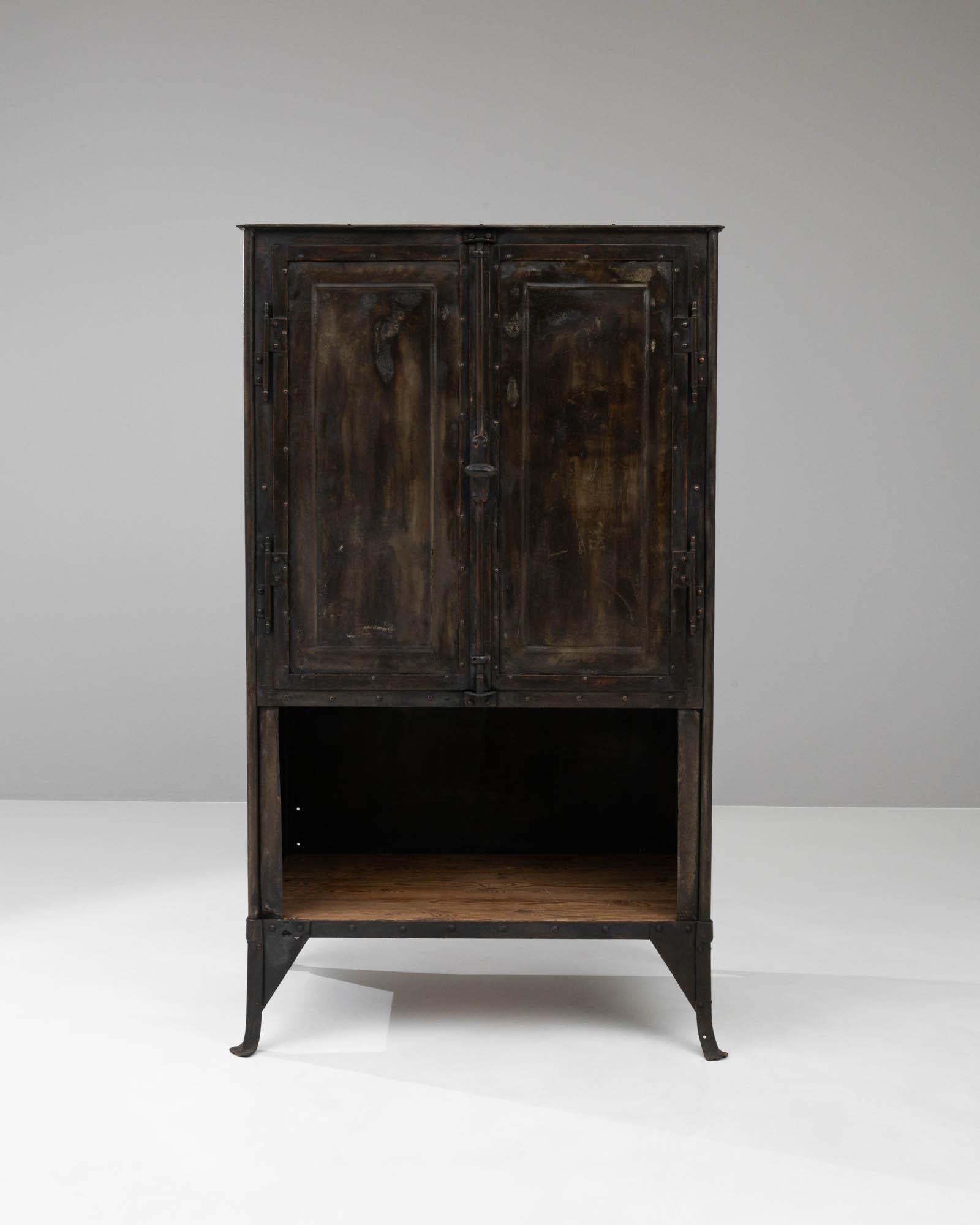 Discover the rugged charm and practicality of this early 1900s French metal cabinet, a truly distinctive piece that adds both character and utility to your space. Crafted with sturdy metal and featuring a contrasting wooden shelf, this cabinet