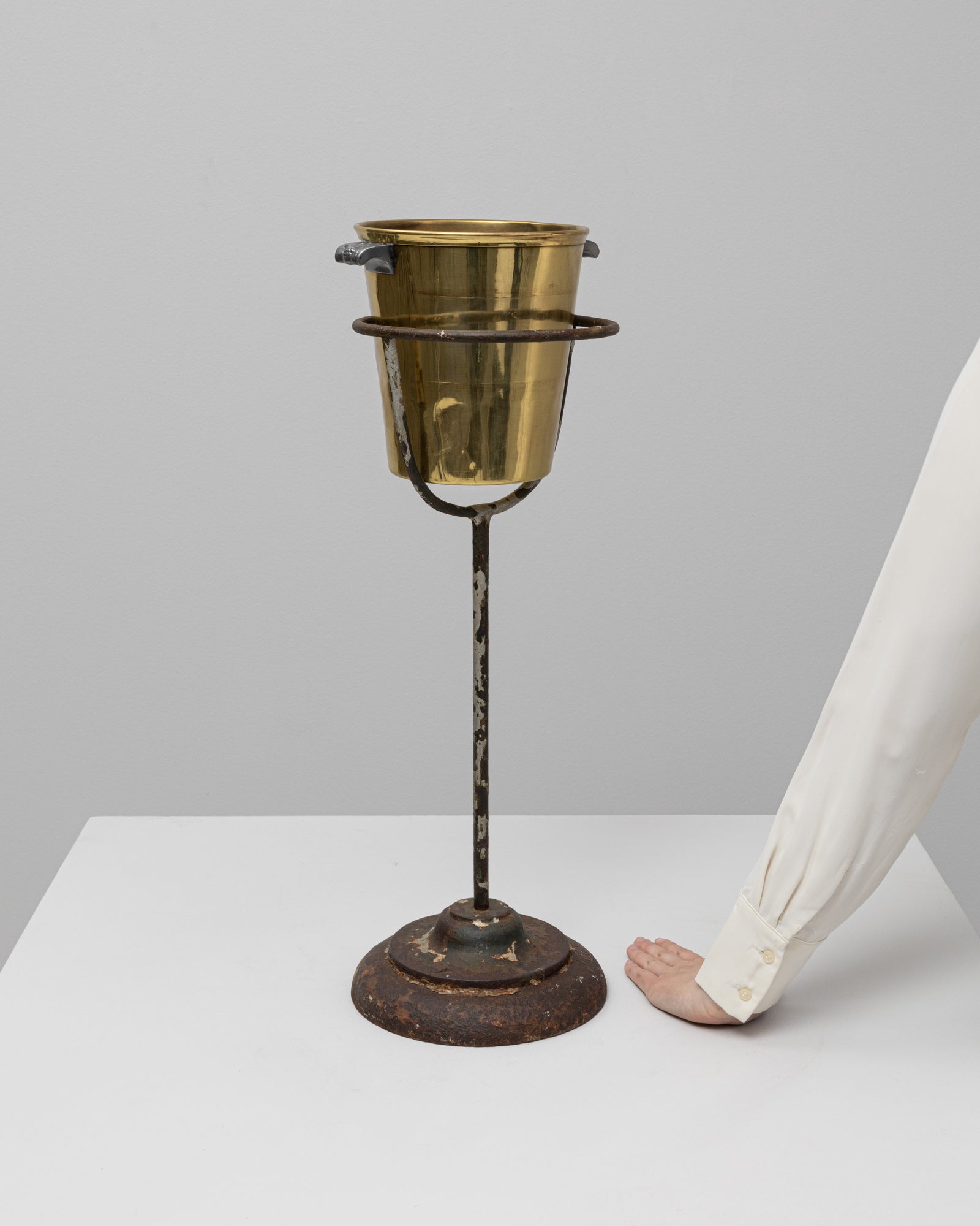 Französischer Eiskübelständer aus Metall um 1900. Dieser antike Ständer besteht aus einem stabilen gusseisernen Sockel mit einem schlanken, aufrechten Stiel, der eine runde Halterung für einen traditionellen Sekt- oder Weinkübel trägt. Mit Spuren