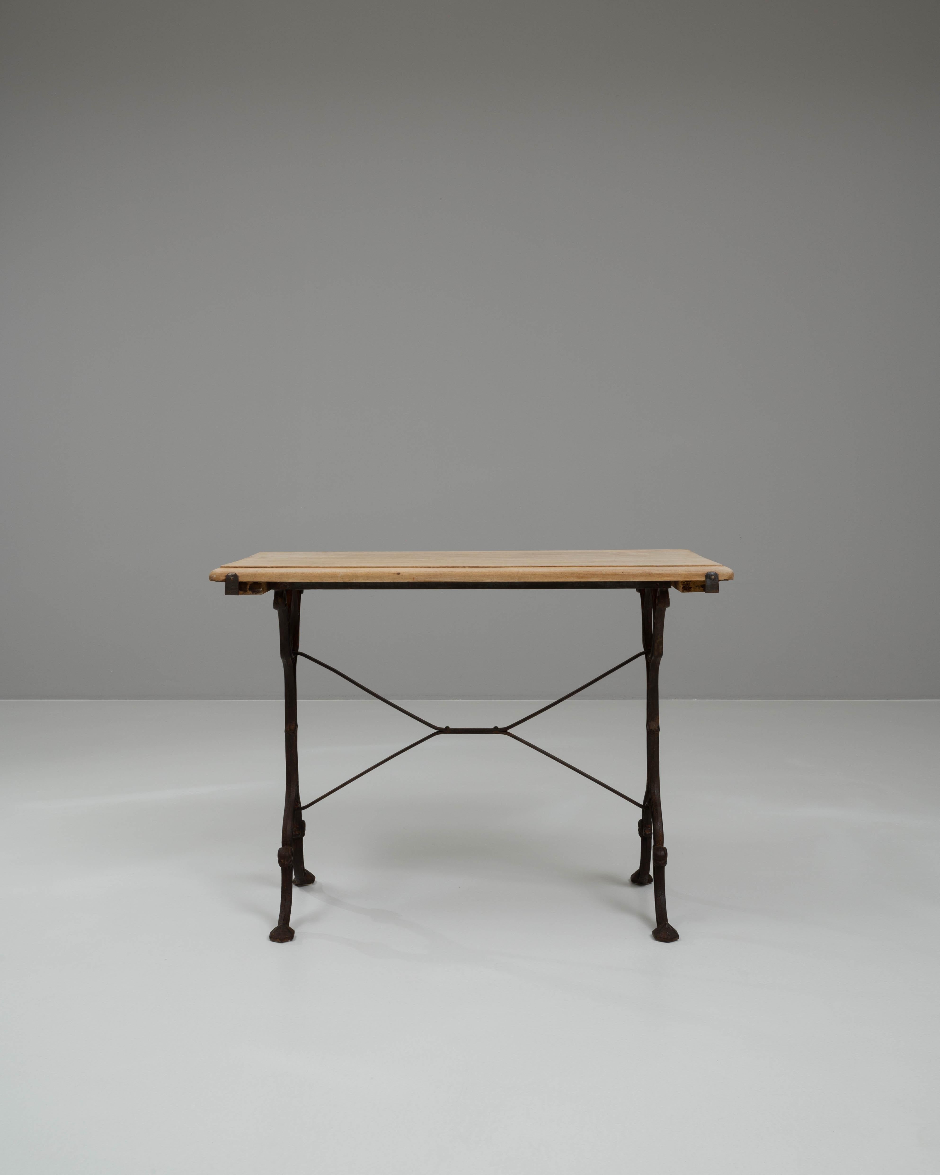 This early 20th-century French side table showcases the perfect balance between industrial craftsmanship and timeless simplicity. Featuring a solid cast iron base with elegant curved legs and cross-stretcher supports, the design offers both