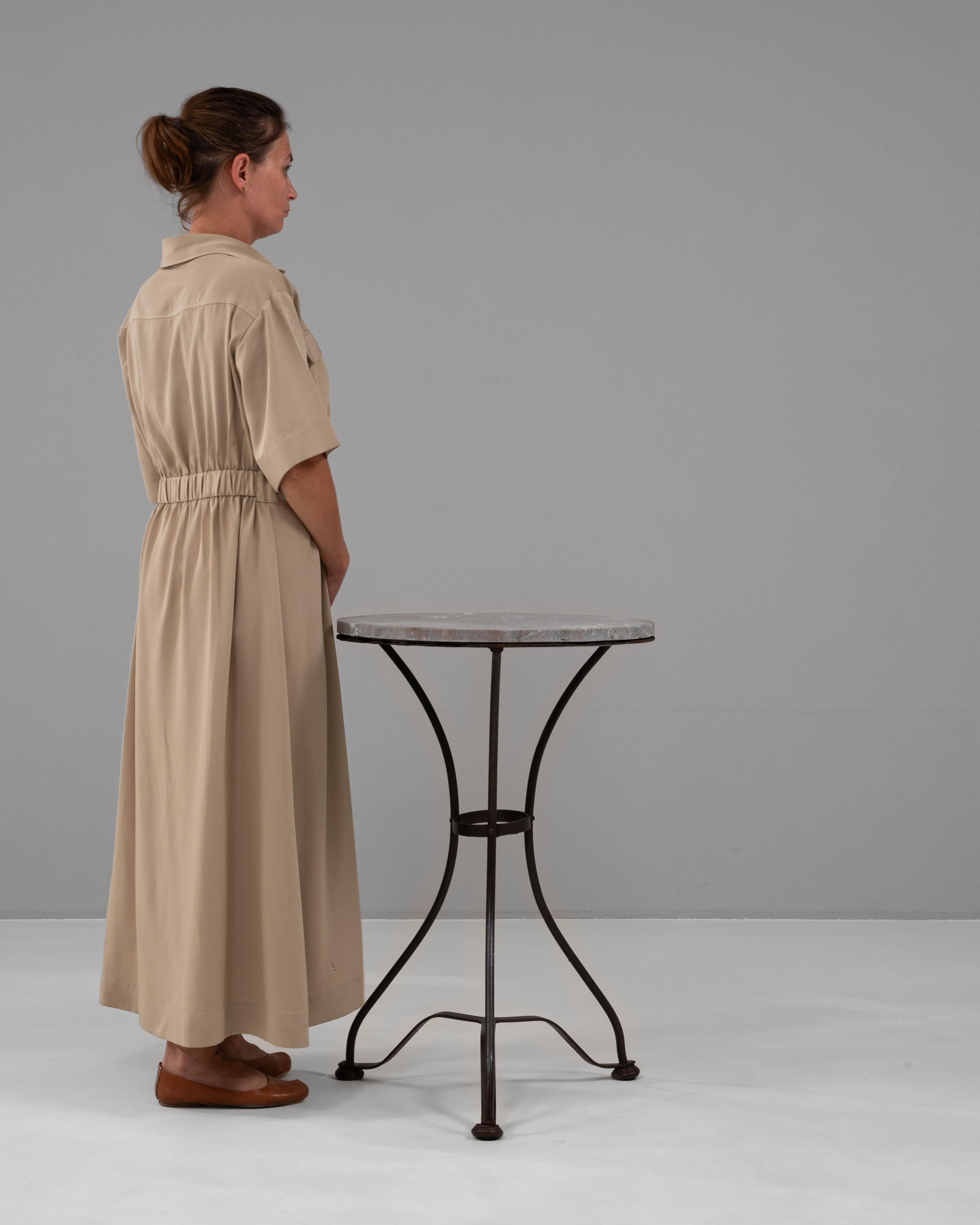 This 1900s French metal table with a marble top embodies a timeless combination of elegance and durability. The slender iron base features graceful curves and a sturdy structure, perfectly complementing the polished marble surface. The marble top,