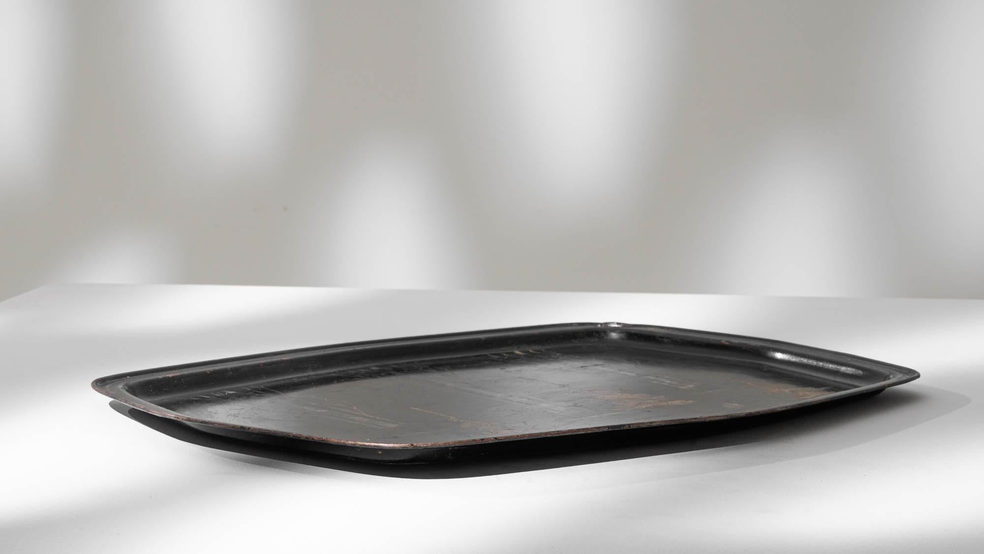 Transport yourself to the scenic beauty of the French countryside with this exquisite 1900s French metal tray. Crafted with meticulous attention to detail, the black tray serves as a canvas for a captivating depiction of nature's splendor. Delicate