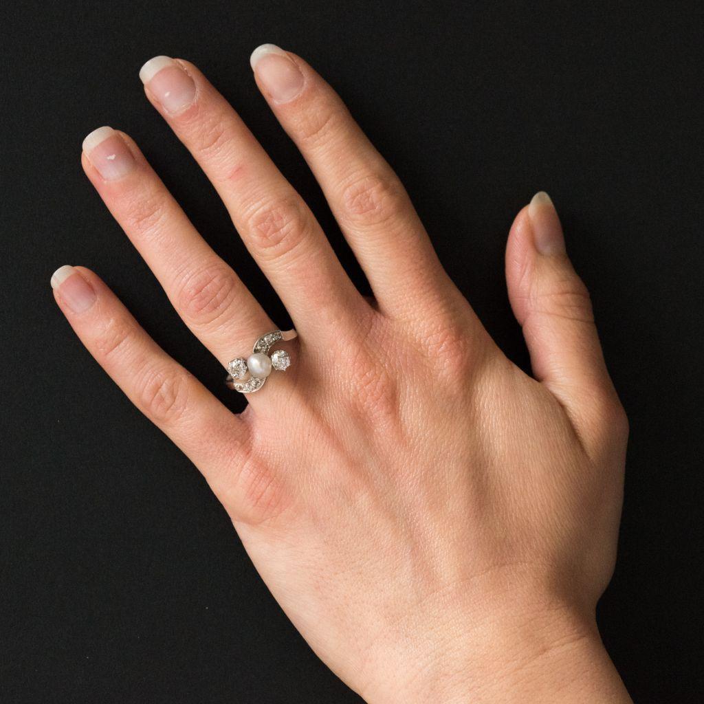Ring aus rhodiniertem 18-karätigem Weißgold, mit Adlerkopfpunze.
Dieser erhabene antike Ring formt eine elegante Kurve, die mit 6 Diamanten im Antikschliff besetzt ist.
In der Mitte ist eine authentische Barockperle mit schillernden Nuancen gefasst,