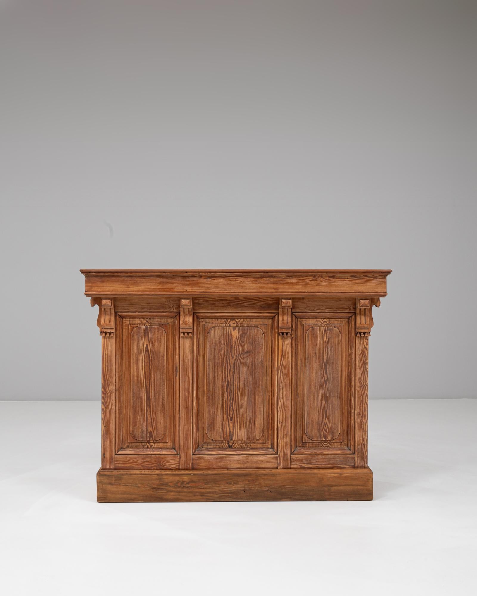 Diese französische neoklassizistische Holzbar aus dem Jahr 1900 zeichnet sich durch zeitlose Handwerkskunst, starke architektonische Details und eine warme Patina aus. Die drei getäfelten Fronten, die jeweils von kannelierten Pilastern eingerahmt