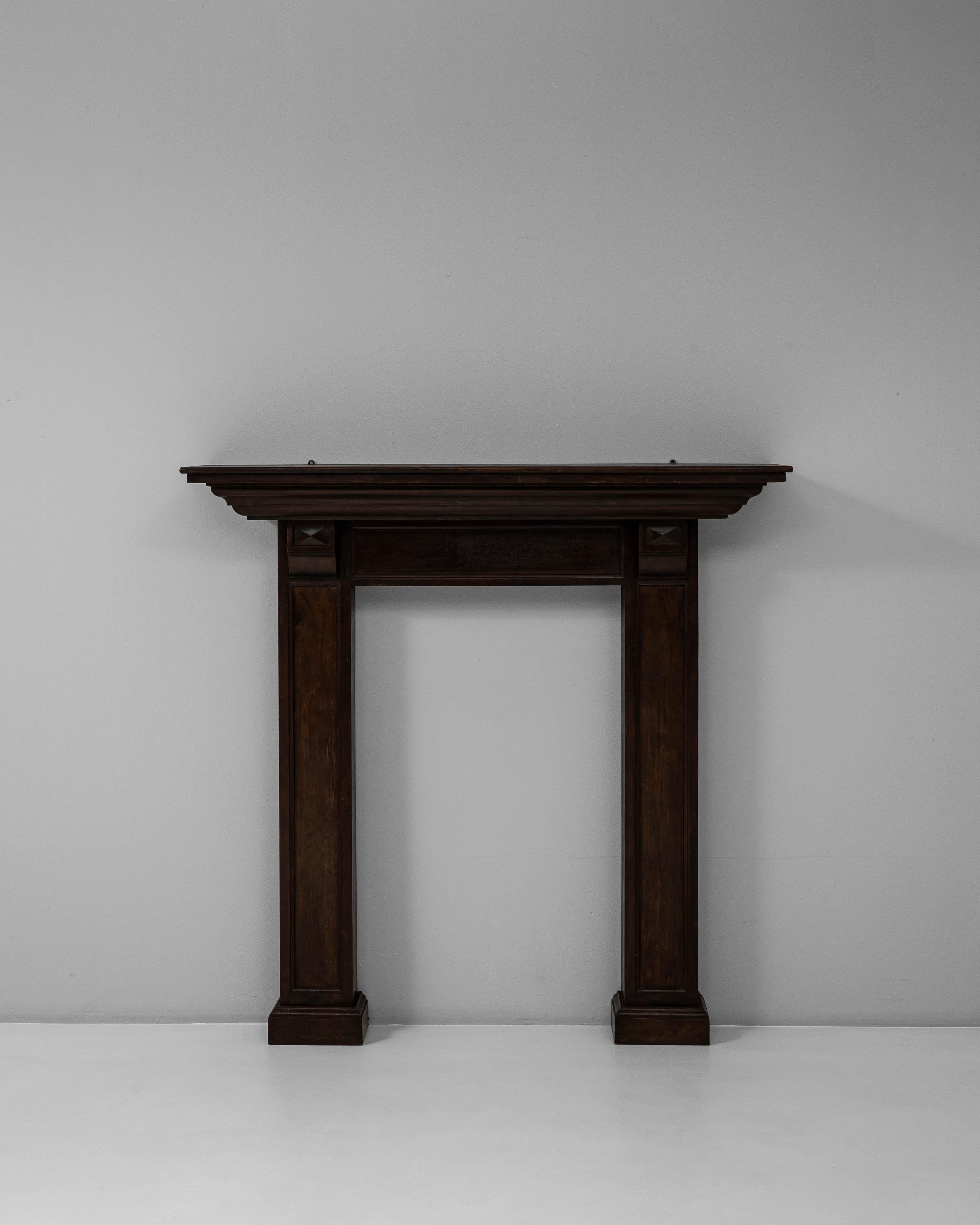 Esta repisa de chimenea de madera neoclásica francesa de 1900 con pátina original ejemplifica la simetría atemporal y la elegancia arquitectónica del diseño de principios del siglo XX. Fabricado en madera de tonos intensos, presenta líneas limpias,