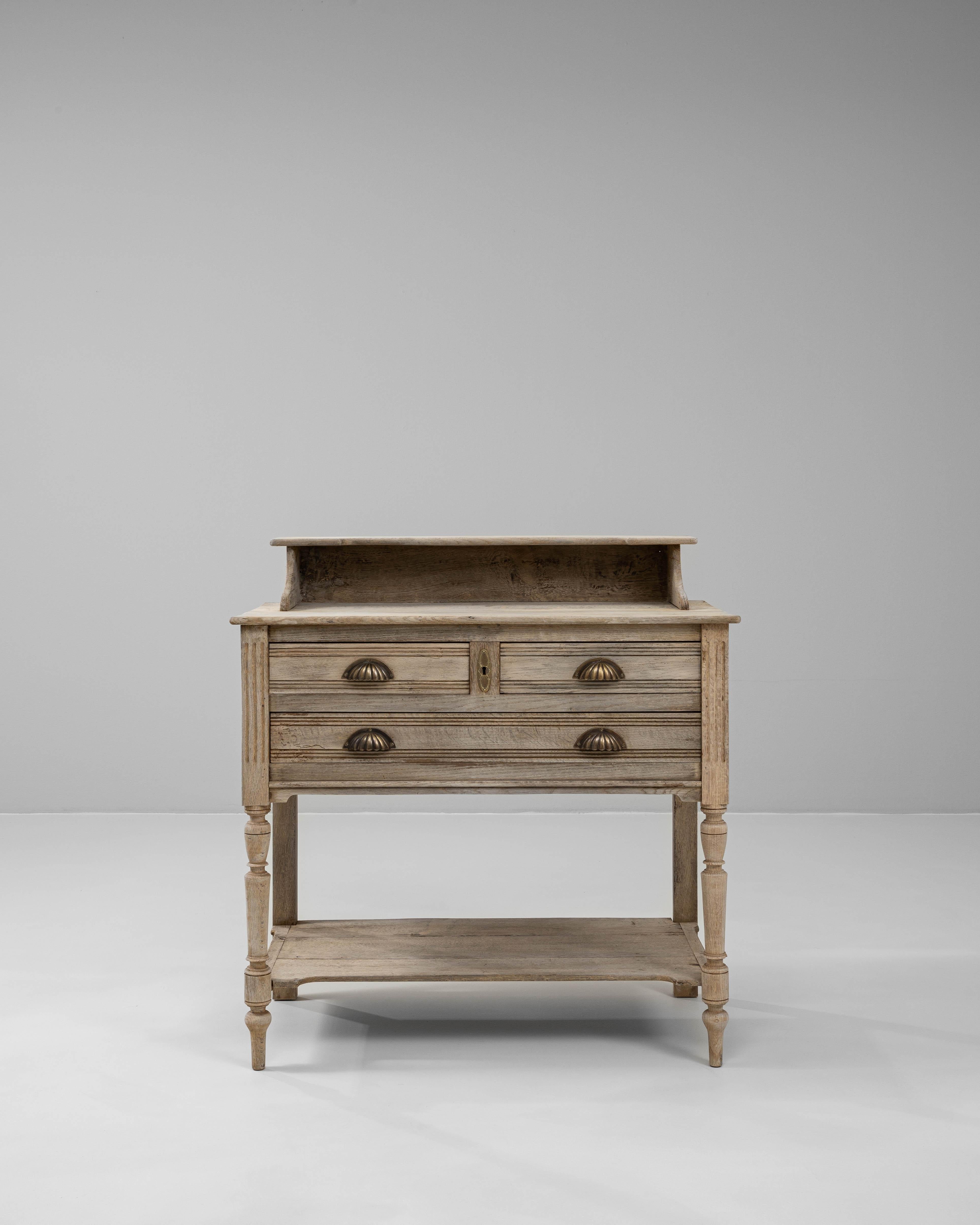 This 1900s French oak desk exemplifies early 20th-century provincial charm with its understated elegance and utilitarian design. Crafted from solid oak, the piece features a gently weathered finish that enhances the natural texture of the wood. The