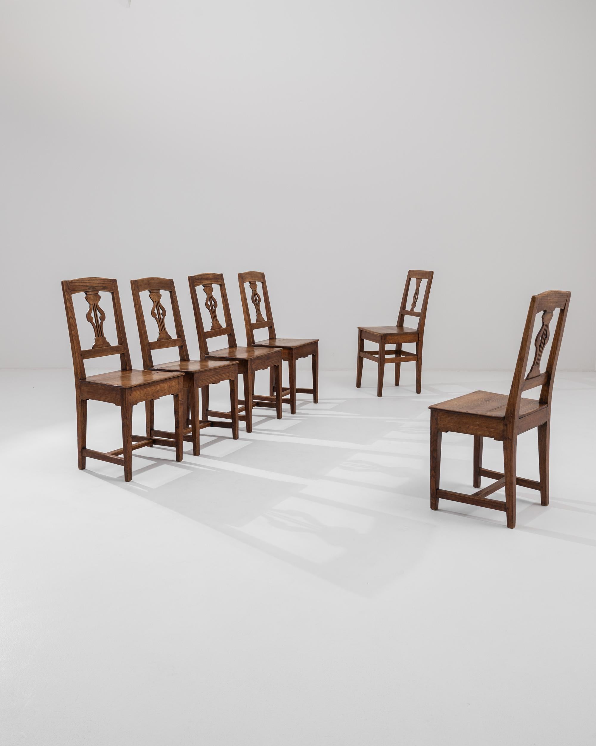 This set of six turn of the century dining chairs combines a graceful shape with a beautiful patina. Made in France, the design takes inspiration from the restrained elegance of Biedermeier furniture. Lyre-shaped splats lend a poetic note to the