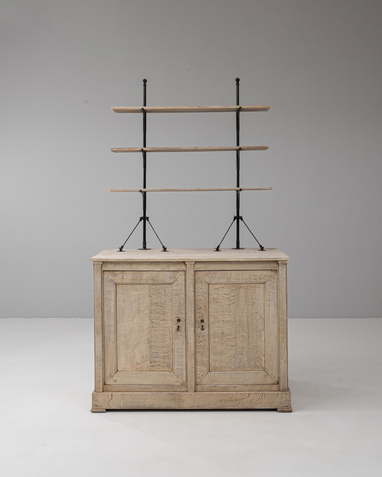 Questa vetrina francese del 1900 è realizzata in rovere massiccio e presenta una splendida finitura naturale patinata che ne esalta il carattere senza tempo. La base dell'armadietto offre un ampio spazio di archiviazione dietro le ante a pannello,