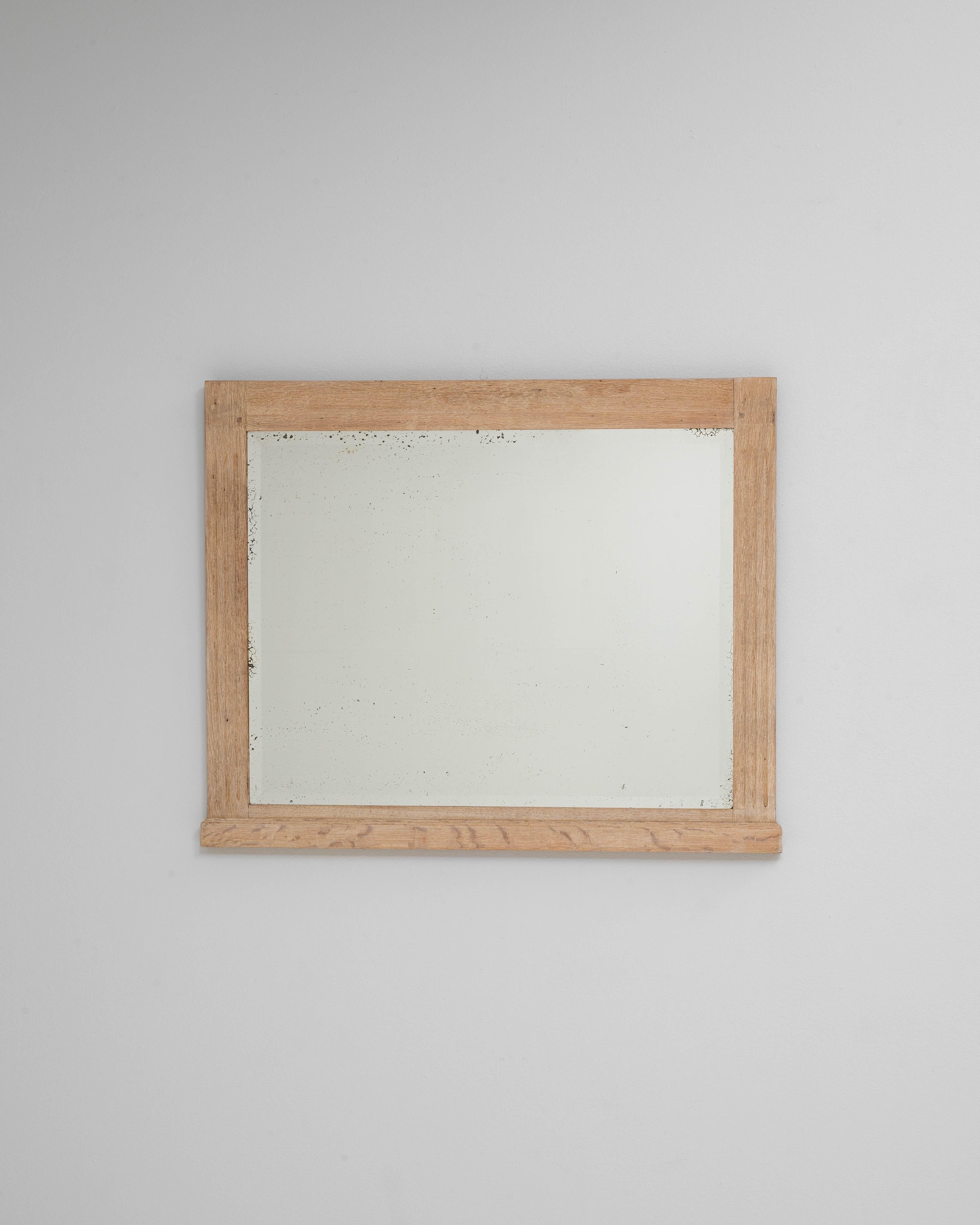 Questo specchio in rovere francese del 1900 presenta una silhouette pulita e sobria che mette in risalto la bellezza naturale dei suoi materiali. La cornice in rovere leggermente patinato conserva il suo carattere originale, mostrando un tono caldo